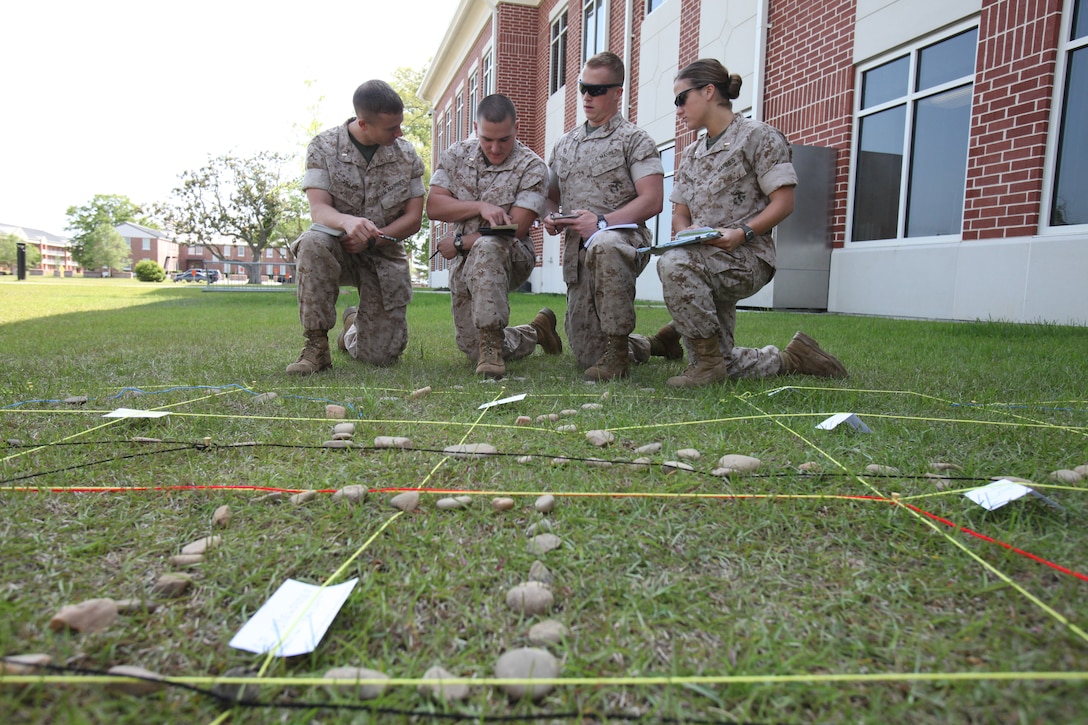 From left to right, 2nd Lts. Charles M. Felps, Brian C. Neri, James D. Glover and Kathryn M. Wichard review their notes and create a plan of action for calling in practice airstrikes against targets on a terrain model of a Camp Lejeune bombing range, behind the headquarters building aboard Marine Corps Air Station Cherry Point May 12. The training helped them prepare for an upcoming exercise where they would call in for aircraft to practice airstrikes at Camp Lejeune.