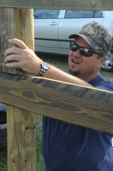 QUITMAN, Ga. -- Jeff Abney, volunteer, holds a slab of wood in place in order to get proper placement distance at a riding facility May 11. In addition to helping reconstruct, Mr. Abney was part of a team of Air Force volunteers who reconstructed a new riding arena for a facility dedicated to helping veterans recover from post-traumatic stress disorder. (U.S. Air Force photo/Airman 1st Class Paul Francis)