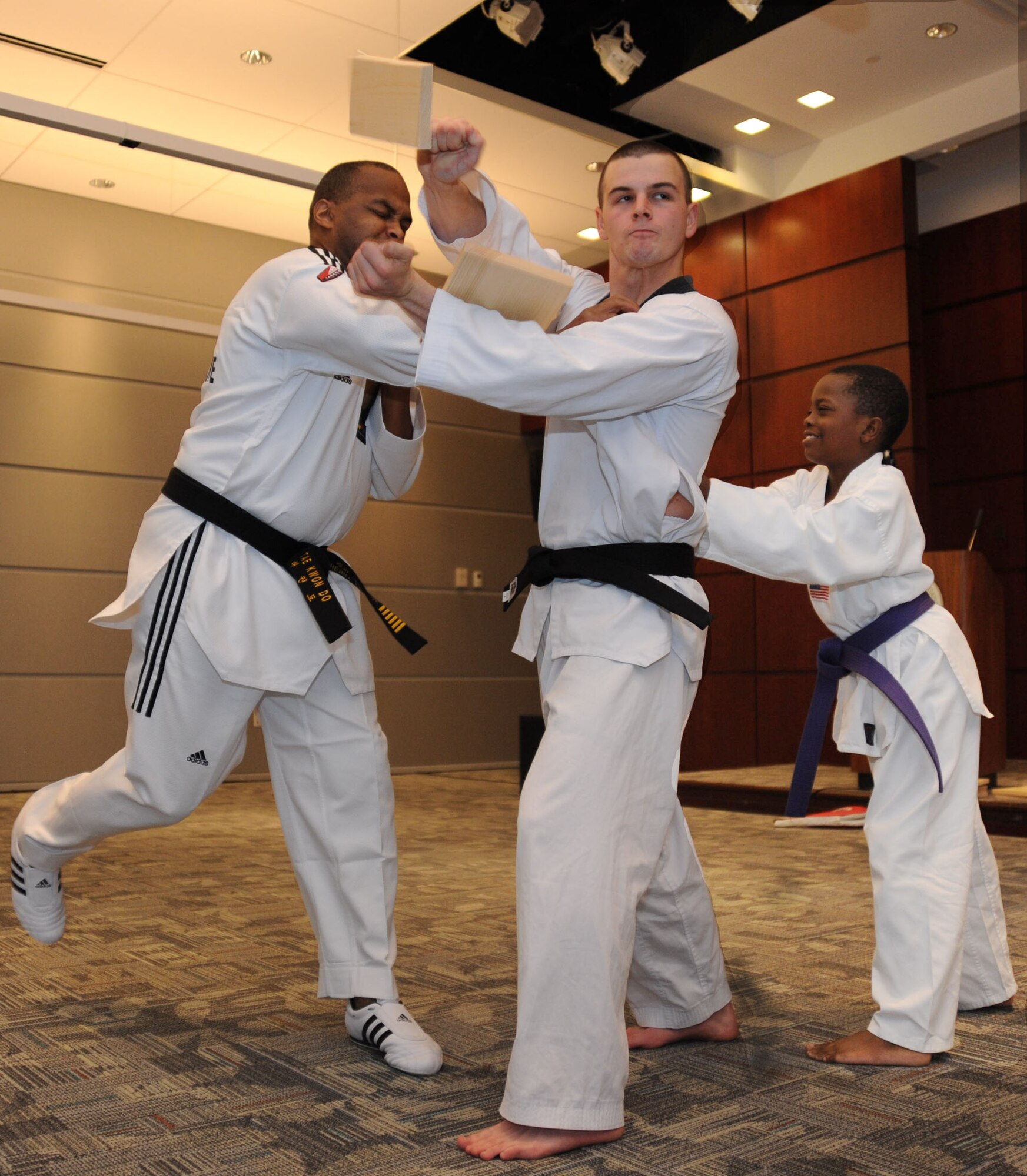 Tae Kwon Do Master Black Belt Lt. Col. Henry Lane of Air Force District of Washington's Lessons Learned breaks a one inch thick board held by 779th Medical Support Squadron logistics technician Airman 1st Class Shane Borodycia during a health and wellness demonstration May 11 at the U.S. Department of Transportation's Headquarters, Washington, D.C. The Airmen are backed up by 8-year-old Chris Atkins, who attends Tae Kwon Do classes led by Colonel Lane at Joint Base Anacostia-Bolling, Washington D.C. (USAF Photo by Benjamin Newell)