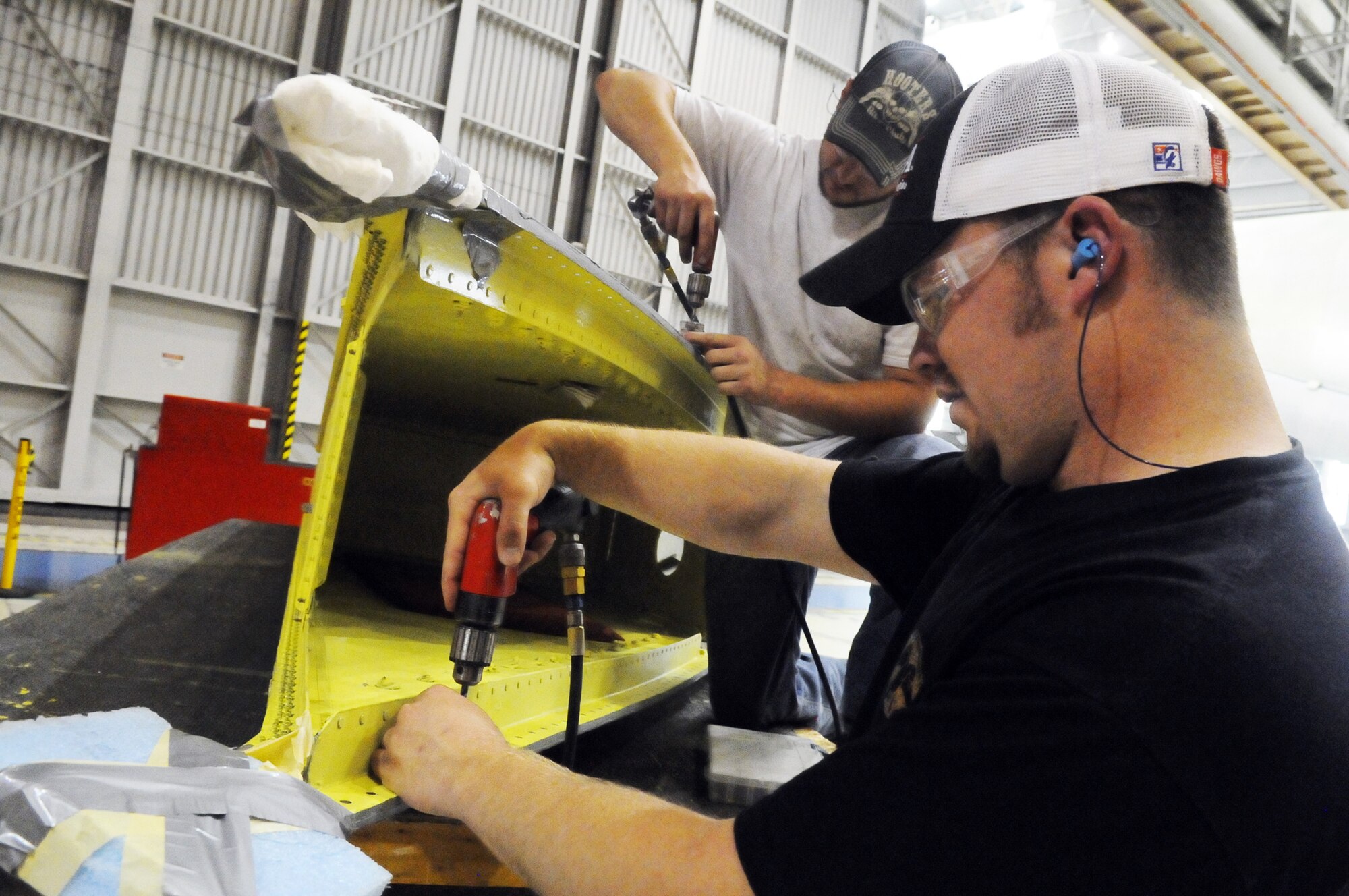 Craig Pearce and Luke Beard, aircraft sheet metal mechanics, drill holes in a C-5 wing box. U. S. Air Force photo by Sue Sapp