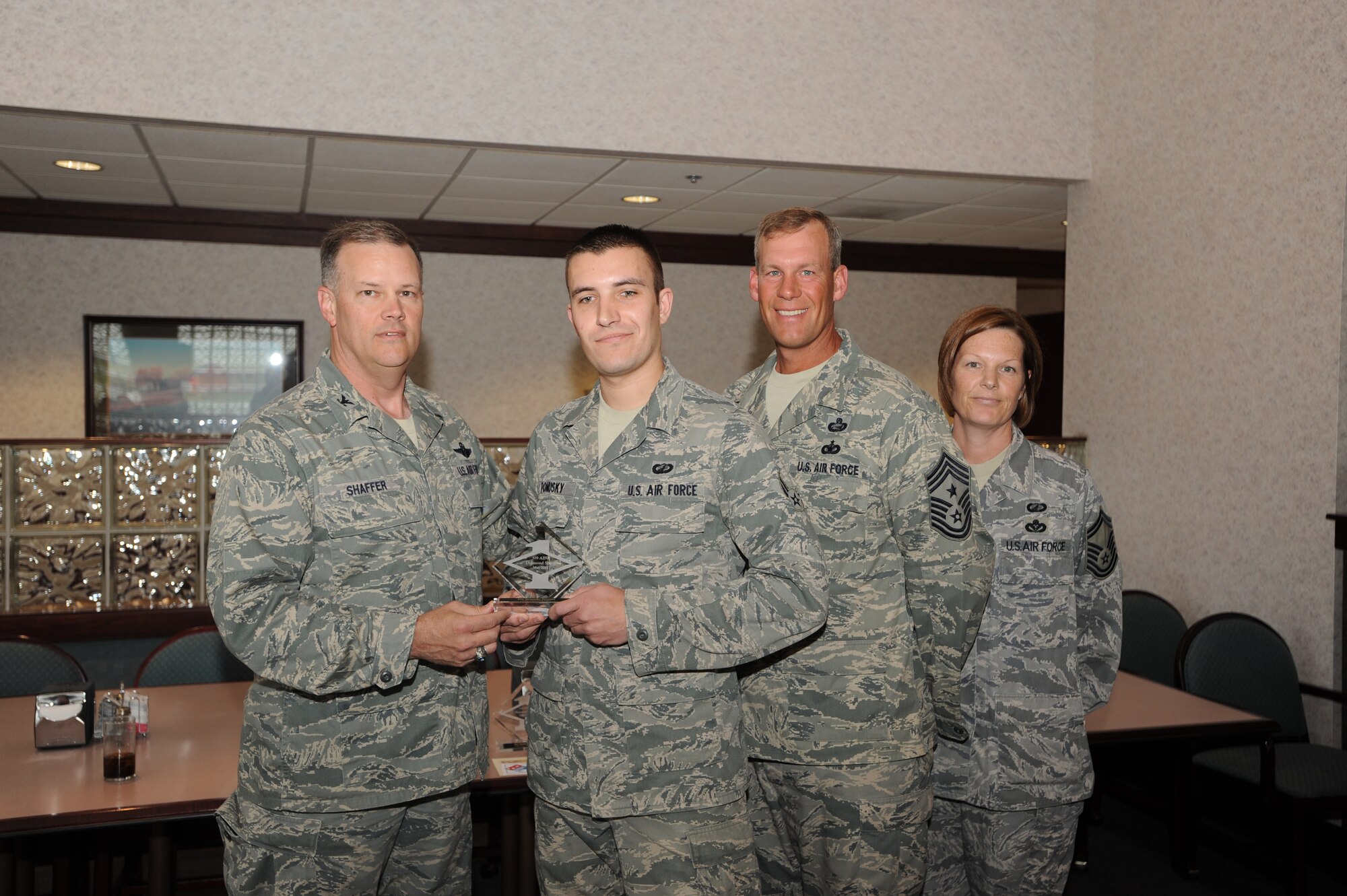Col. Don Shaffer, 319th Air Base Wing commander, presents Airman 1st Class Alexander Ponusky, 319th Contracting Squadron, with a Diamond Sharp Award May 11 at Airey Dining Facility here, accompanied by Command Chief Master Sgt. David Carlson, 319th Air Base Wing, and Master Sgt. Luca Dudley, 319th Force Support Squadron first sergeant. The Diamond Sharp Award is given to those Airmen who epitomize service before self and strive for excellence at work and off duty. (U.S. Air Force photo by Staff Sgt. Suellyn Nuckolls)
