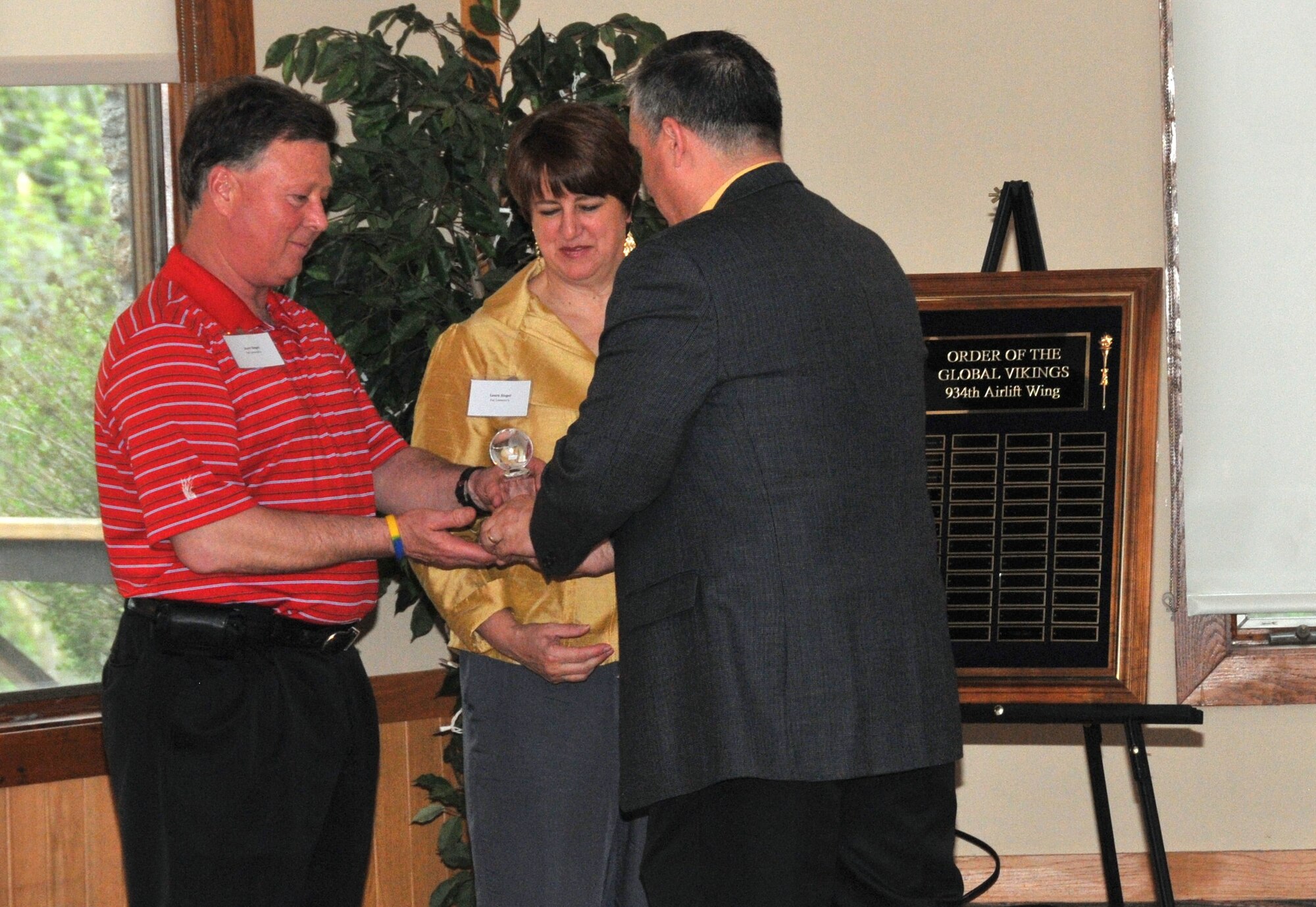 Col. Darrell G. Young, 934th Airlift Wing commander presents Scott and Laura Siegel with a crystal globe signifying their induction into the Order of the Global Vikings May 11. The Siegels have been major supporters of the 934th Airlift Wing and other military organizations.