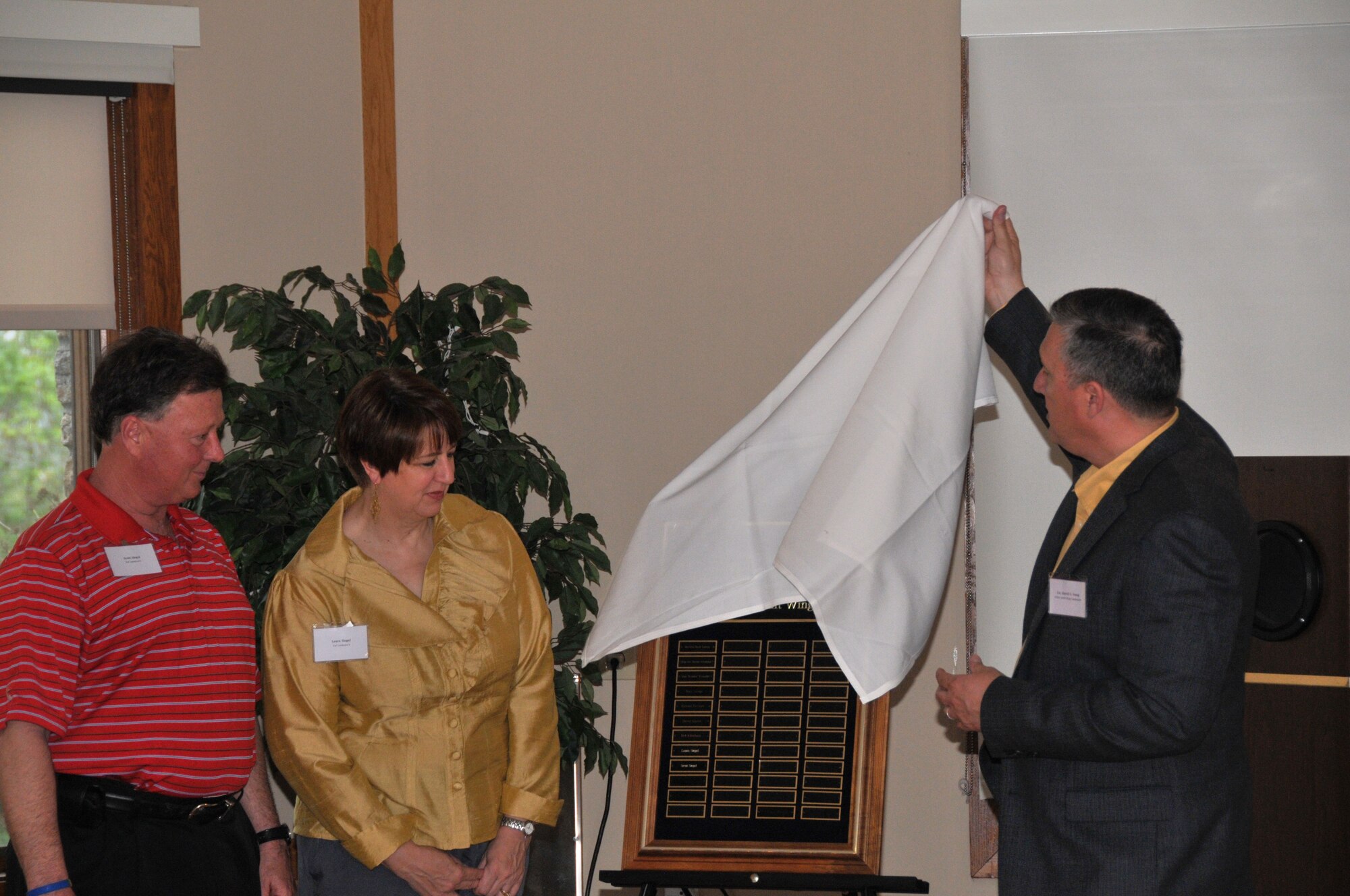 Col. Darrell G. Young, 934th Airlift Wing commander, unveils the Order of the Global Vikings plaque signifying the induction of Scott and Laura Siegel into the order May 11. The Siegels have been major supporters of the 934th Airlift Wing and other military organizations.