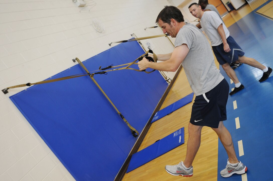 Staff Sgt. Keith Miller, 633d Force Support Squadron fitness specialist, instructs Jim Taccogno, spouse of 1st Lt Sharee Taccogno, 633d Medical Group inpatient clinical nurse, during a TRX Suspension Training demonstration in Shellbank Fitness Center at Langley Air Force Base, Va., May 10, 2011. TRX is a type of training that uses your own body weight and gravity to build strength, balance, coordination, flexibility, core and joint stability, all while preventing injuries.  (U.S. Air Force photo by Airman 1st Class Kayla Newman/Released)