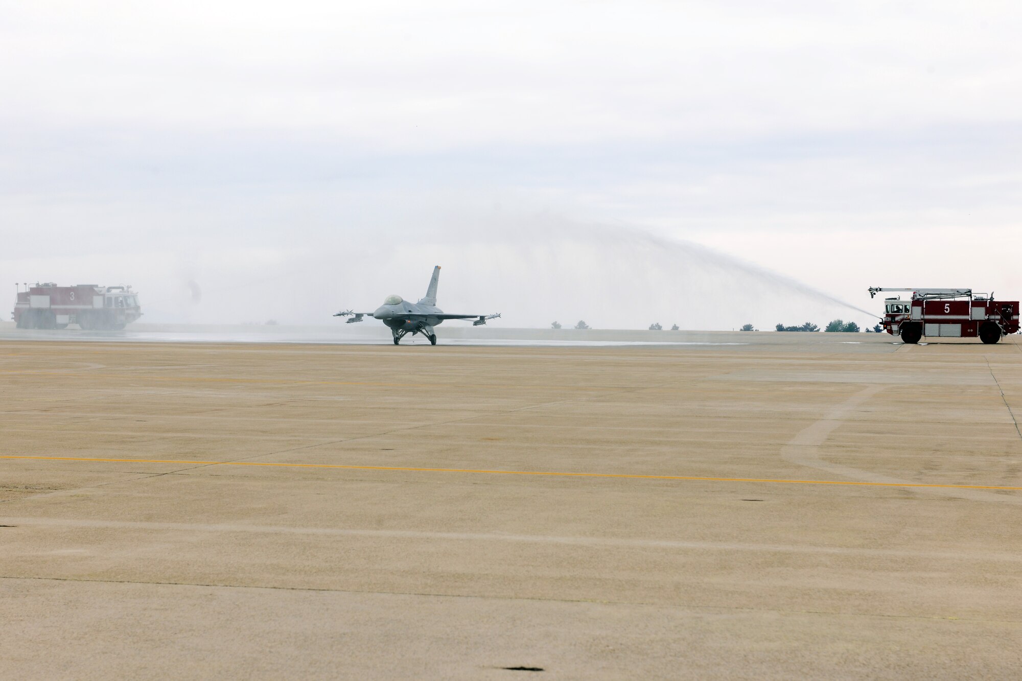 KUNSAN AIR BASE, Republic of Korea -- Col. John Dolan, 8th Fighter Wing commander, taxies his F-16 Fighting Falcon on the flightline as fire trucks from the 8th Civil Engineer Squadron, spray water across the jet during his fini flight here May 12. The fini-flight is a long standing practice of both the United States and Royal Australian Air Forces to commemorate a commander’s departure from an installation. Colonel Dolan was known as Wolf 50. (U.S. Air Force photo/Senior Airman Brittany Y. Bateman)
