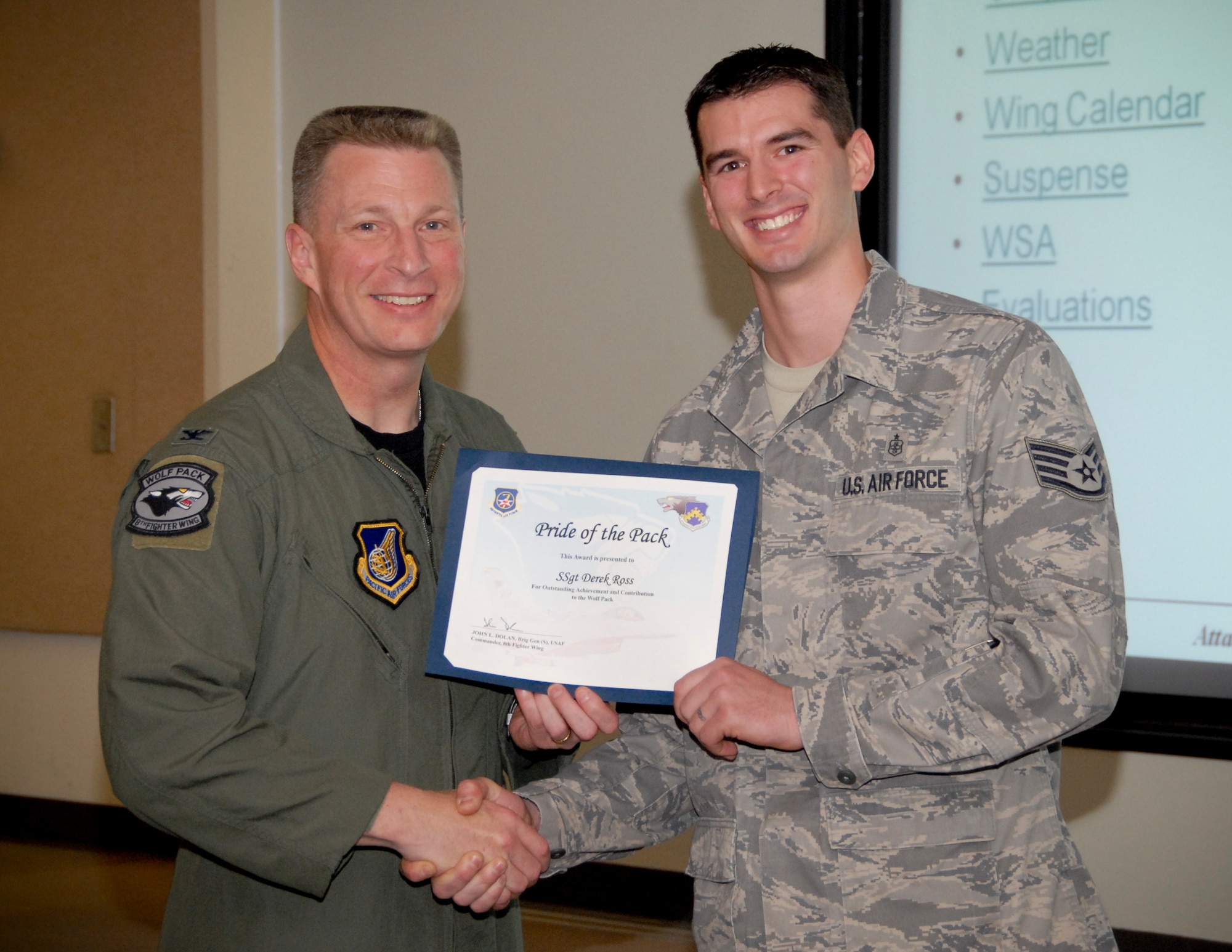 KUNSAN AIR BASE, Republic of Korea -- Col. John Dolan, 8th Fighter Wing commander, presents Staff Sgt. Derrek Ross, 8th Medical Support Squadron, with a Pride of the Pack award here May 12. (U.S. Air Force photo/Capt. Sheryll Klinkel)