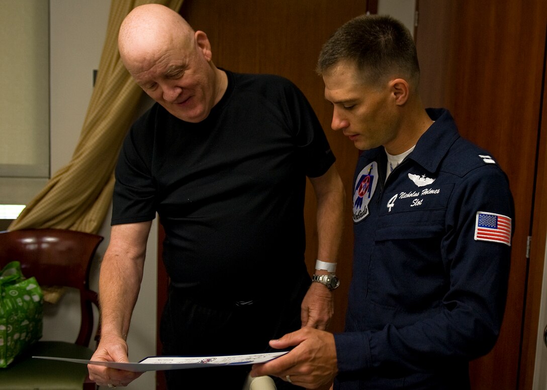 Capt. Nicolas Holmes, U.S. Air Force Thunderbirds pilot, hands Archie Roberts, Hampton Veteran Affairs Medical Center patient, a lithograph of the Thunderbirds team during a visit to the medical center in Hampton Va., May 13, 2011. As Air Force ambassadors who travel the world over, the Thunderbird team strives to showcase the integrity, selfless service and excellence embodied by American Airmen everywhere. (U.S. Air Force photo by Senior Airman Zachary Wolf)(RELEASED)