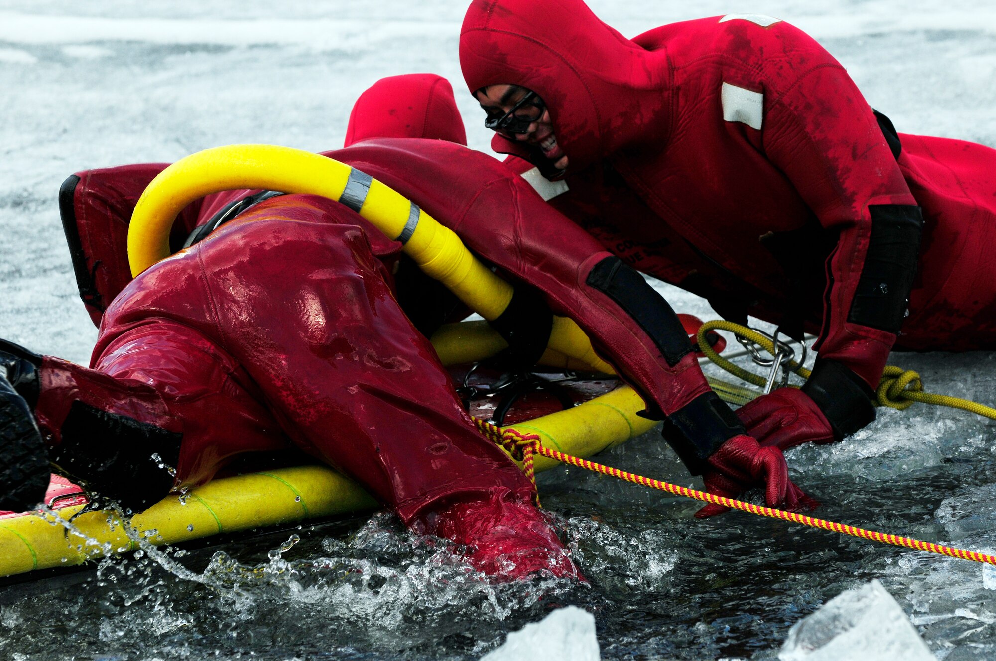 Airman 1st Class David Piasecki climbs out of a frozen lake onto a life raft that Senior Airman Bao Hoang stabilizes with his body during ice water rescue training May 6, 2011, Eielson Air Force Base, Alaska. Emergency rescue Airmen train to stay prepared in the event of an emergency since Alaska lakes are frozen nine to 10 months of the year. Airmen Hoang and Piasecki are fire fighters assigned to the 354th Civil Engineer Squadron Fire Protection Flight. (U.S. Air Force photo/Airman 1st Class Laura Goodgame)
