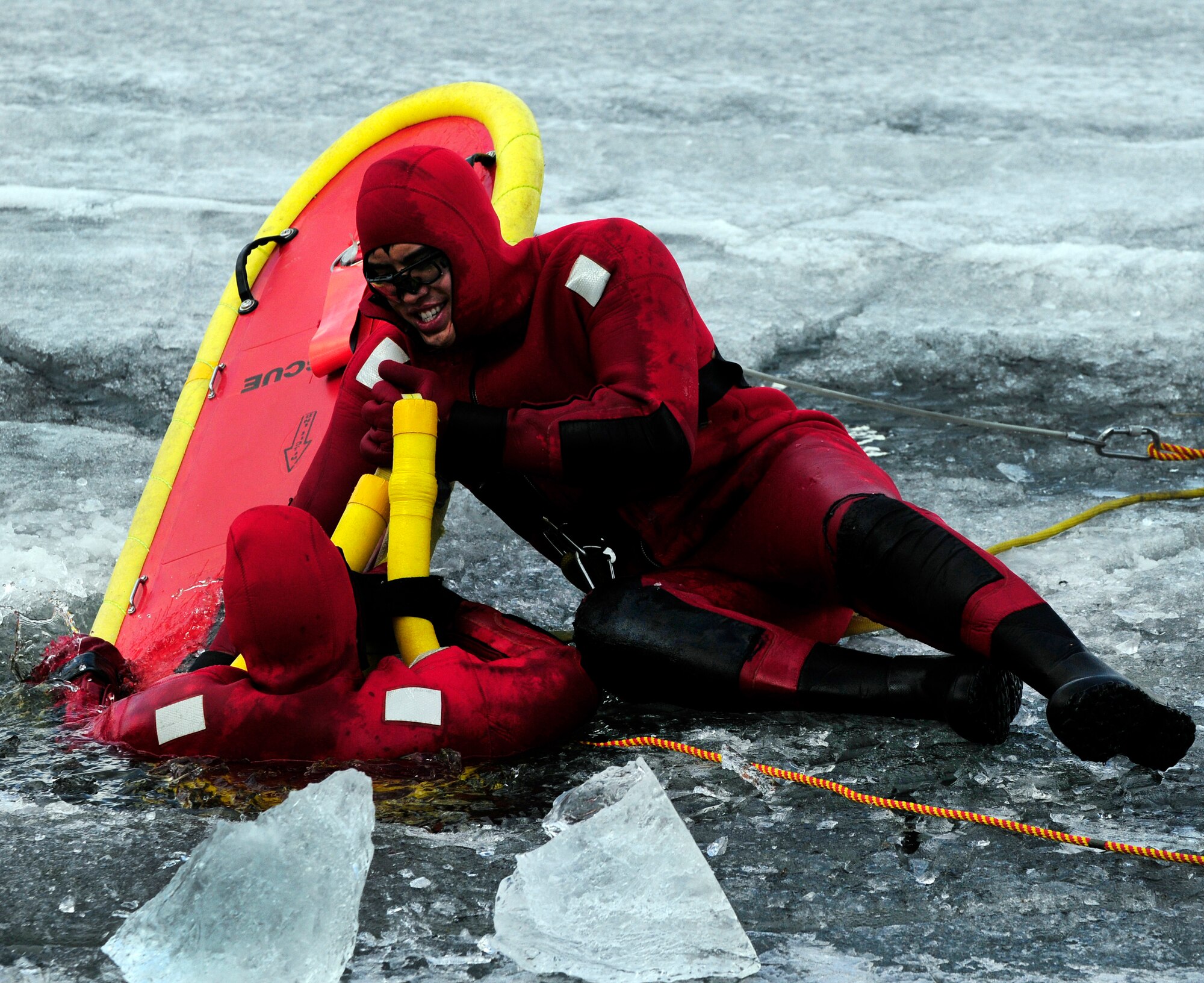 Airman 1st Class David Piasecki climbs out of a frozen lake onto a life raft that Senior Airman Bao Hoang stabilizes with his body during ice water rescue training May 6, 2011, Eielson Air Force Base, Alaska.  Emergency rescue Airmen train to stay prepared in the event of an emergency since Alaska lakes are frozen nine to 10 months of the year. Airmen Hoang and Piasecki are fire fighters assigned to the 354th Civil Engineer Squadron Fire Protection Flight. (U.S. Air Force photo/Airman 1st Class Laura Goodgame)