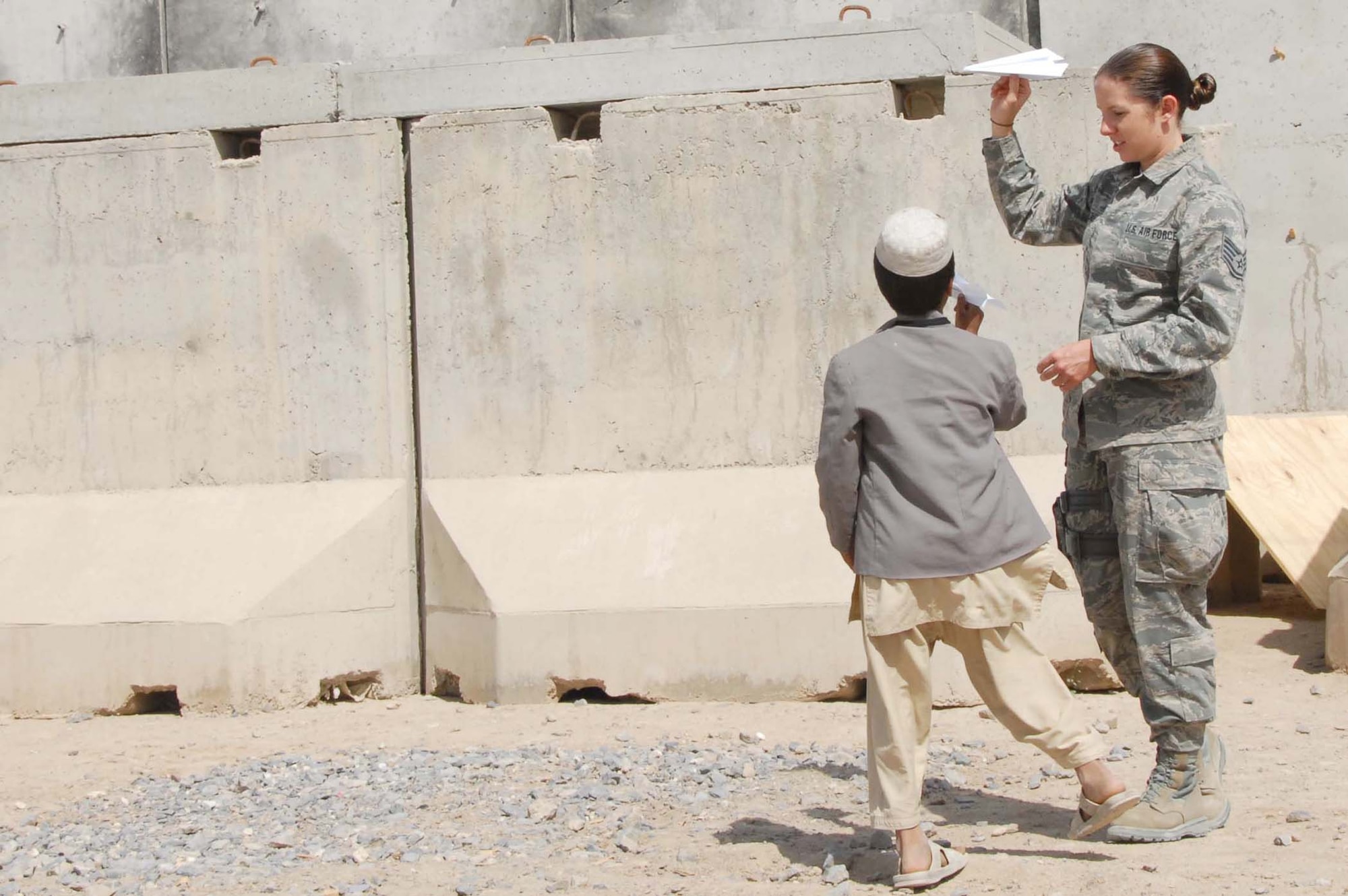 Staff Sgt. Amanda Menlove prepares to show an Afghan boy how to throw a paper airplane at a school April 30, 2011, at Kandahar Airfield, Afghanistan. She is part of a group of Airmen who volunteered to participate in activities at the school for the day that included building the paper airplanes and playing soccer. Sergeant Menlove is assigned to the 451st Air Expeditionary Wing command post at Kandahar Airfield. (U.S. Air Force photo/Tech. Sgt. Emily F. Alley)