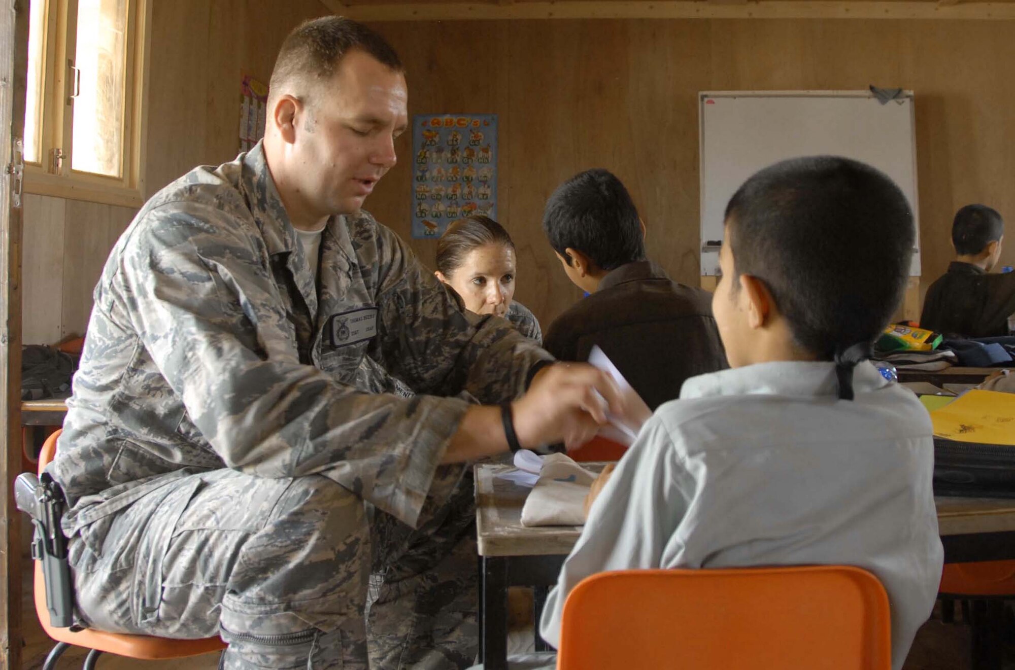 Staff Sgt. Thomas Beers and Staff Sgt. Amanda Menlove demonstrate how to build paper airplanes to Afghan boys at a school April 30, 2011, at Kandahar Airfield, Afghanistan. The two were part of a group of NCOs who volunteered to spend the day with the children and participate in activities such as the building the paper airplanes and playing soccer. (U.S. Air Force photo/Tech. Sgt. Emily F. Alley)