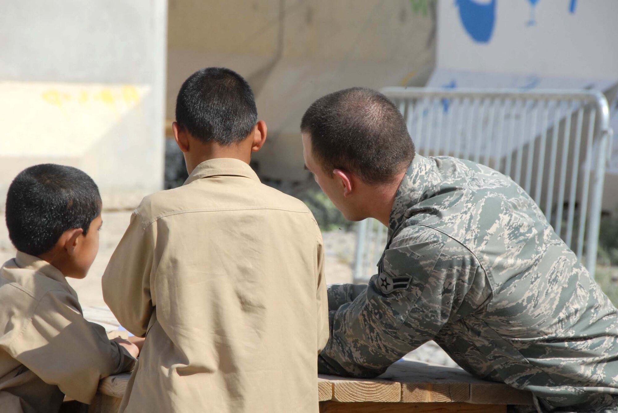 Airman 1st Class Garrett Lee shows Afghan boys how to fold a paper airplane at a school April 30, 2011, at Kandahar Airfield. Airman Lee was part of a group that volunteered to participate in activities for the day, such as building the paper airplanes and playing soccer. Airman Lee works is assigned to the 451st Air Expeditionary Wing command post at Kandahar Airfield. (U.S. Air Force photo/Tech. Sgt. Emily F. Alley)