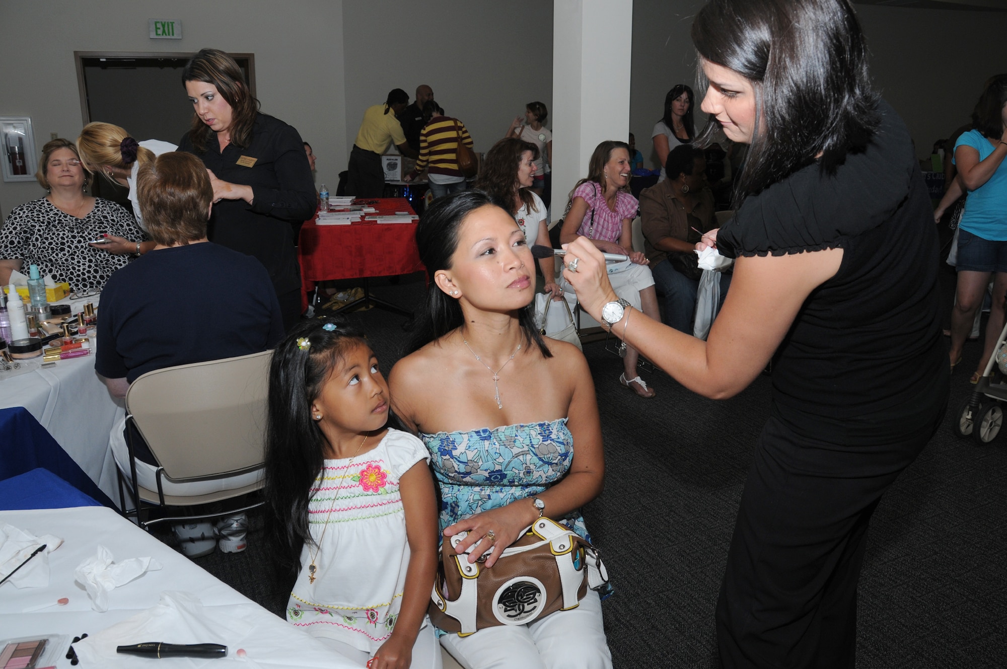From left, Mialani Garcia, 5, watches her mom, Hannah Garcia, receive a makeover
from Jade Braccini, makeup artist at the base exchange. Ms. Garcia is the wife of
Master Chief Petty Officer David Garcia from the Seabee Base in Gulfport.  (U.S. Air Force photo by Kemberly Groue