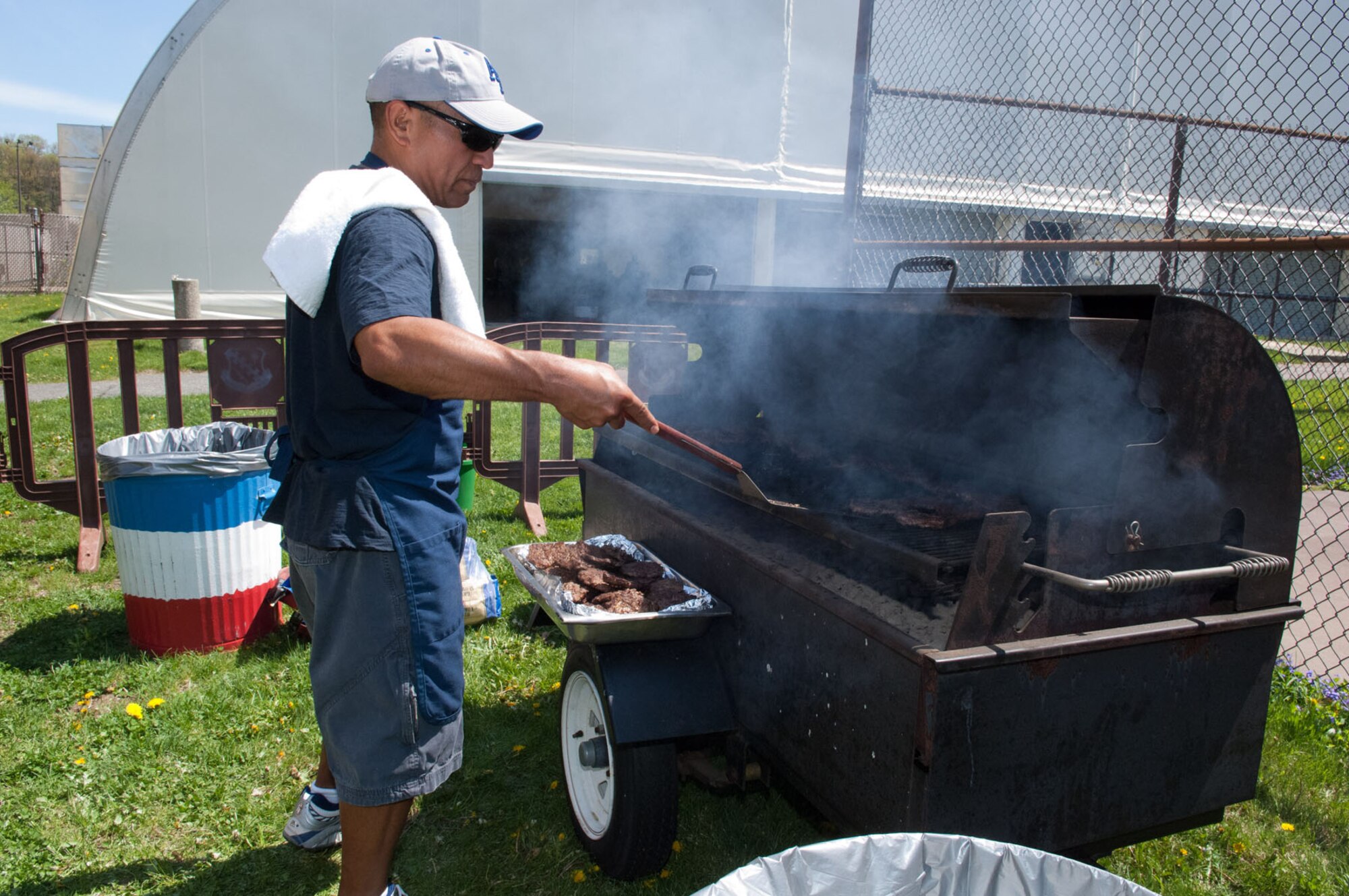 HANSCOM AIR FORCE BASE, Mass. – Chief Master Sgt. Raul Ruiz, Electronic Systems Center first sergeant, flips burgers outside the tennis bubble. Base personnel were invited to a burger burn after the Hanscom Olympics closing ceremonies May 6. Many team and individual activities took place last week, including golf, basketball, dodgeball, racquetball, a build-a-boat contest and more. The 66th Air Base Group took home Hanscom Olympics trophy for having the most points across all events and the Cyber/Netcentric Directorate won the Commander’s Cup. (U.S. Air Force photo by Rick Berry) 