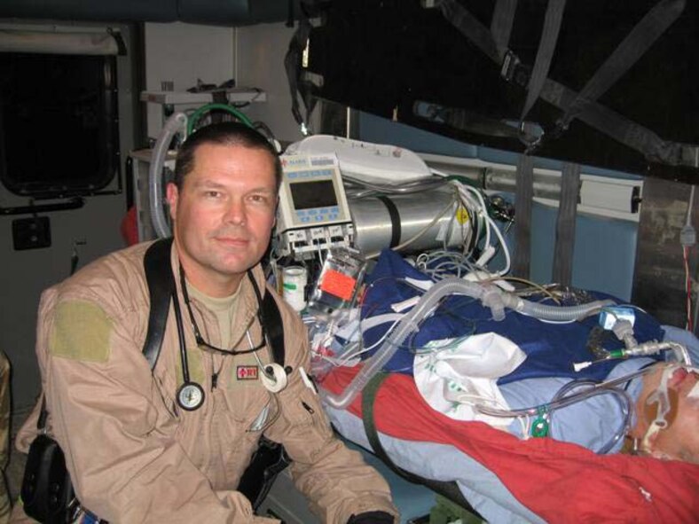 Tech. Sgt. Matthew Blonde sits with a critical patient during a deployment.  Sergeant Blonde, 452nd Aeromedical Staging Squadron, is a member of the Critical Care Aeromedical Transport Team and a full-time, civilian respiratory therapist.  (Photo courtesy of TSgt. Matt Blonde)