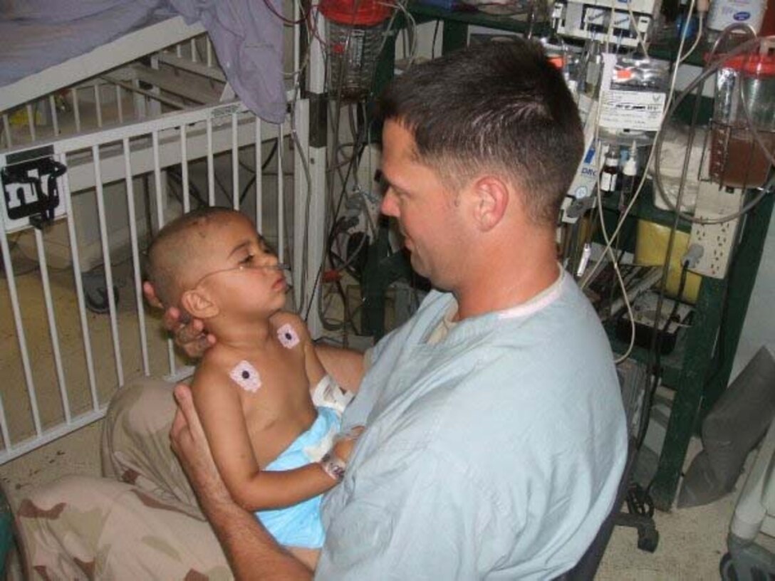 Tech. Sgt. Matthew Blonde holds Sarah, a critically injured Iraqi girl, during a deployment.  Although he doesn't know if she survived, he became quite attached to her and still carries this picture in his wallet.  Sergeant Blonde, 452nd Aeromedical Staging Squadron, is a member of the Critical Care Aeromedical Transport Team and a full-time, civilian respiratory therapist.  (Photo courtesy of TSgt. Matt Blonde)