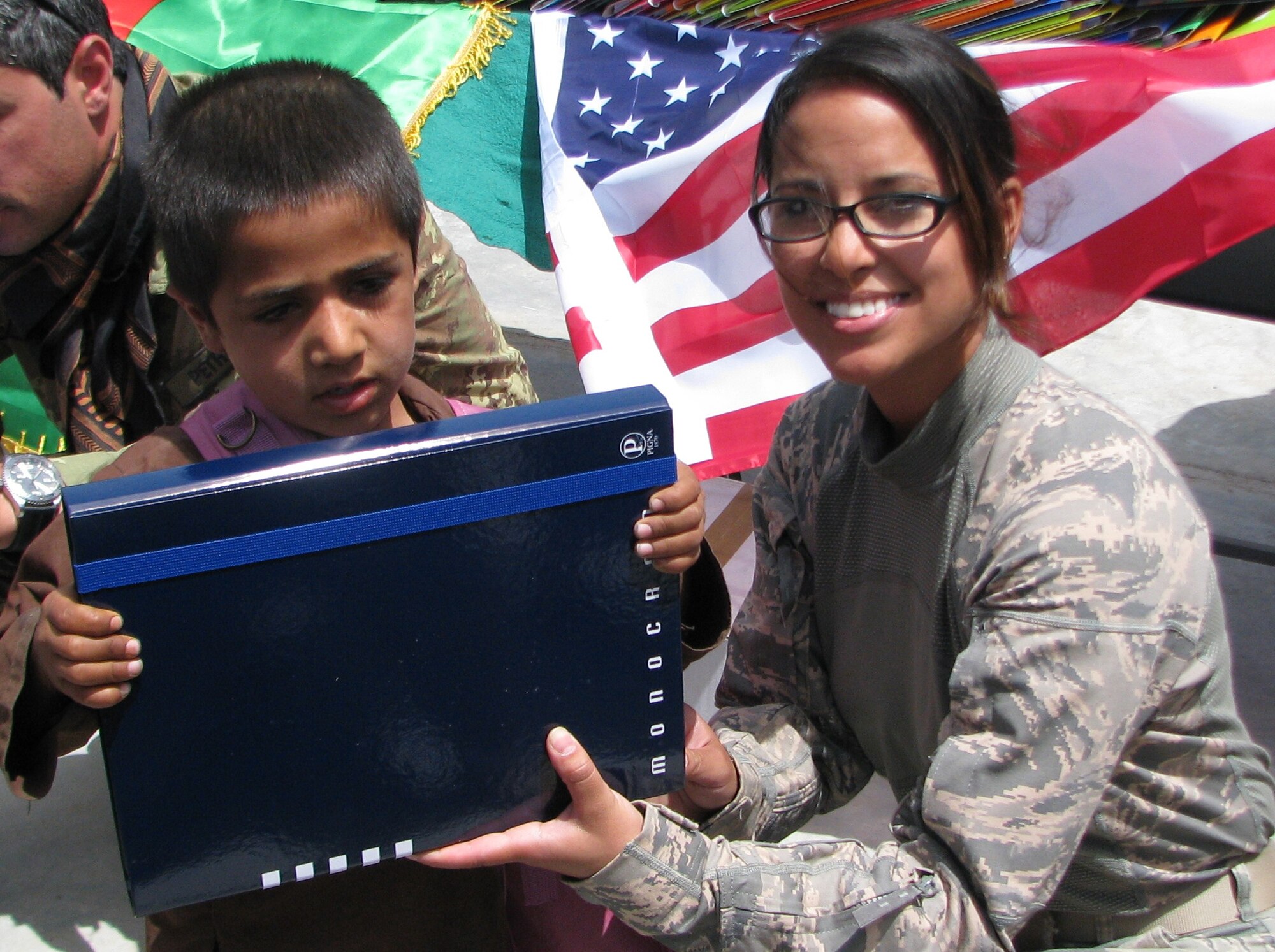 Tech. Sgt. Stacey Duvall, 838th Air Expeditionary Advisory Group, hands a local Afghan child a new folder and backpack May 12. Airmen from the 838th Air Expeditionary Advisory Group worked in conjunction with coalition partners and Afghan allies to help open a school in the village of Mandel located Southwest of Shindand in the Herat Province. (U.S. Air Force photo by Lt. Col. Joe Del Campo)
