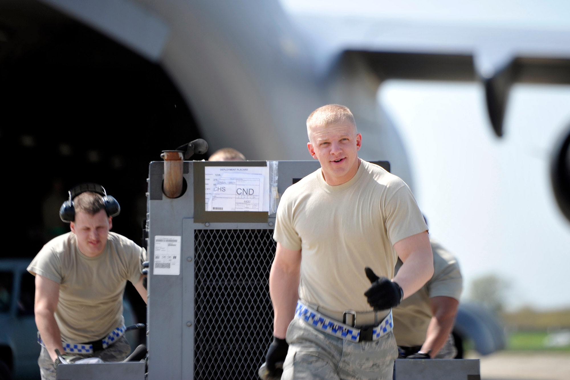 Senior Airman Daniel Mage (left) and Airman 1st Class Adam Hill, both air transportation specialists with the 621st Contingency Response Element off-load equipment from a C-17 Globemaster III at Mihail Kogalniceanu Air Base, May 10.  Fifty-four members of the 621st Contingency Response Wing deployed here to extend airfield capability supporting multi-modal operations during a U.S. Transportation Command  proof-of-principle evaluation. The process is expected to demonstrate the feasibility of using the air base as a hub for equipment flowing into and out of Afghanistan.  (U.S. Air Force photo by Master Sgt. Laura K. Deckman/released)