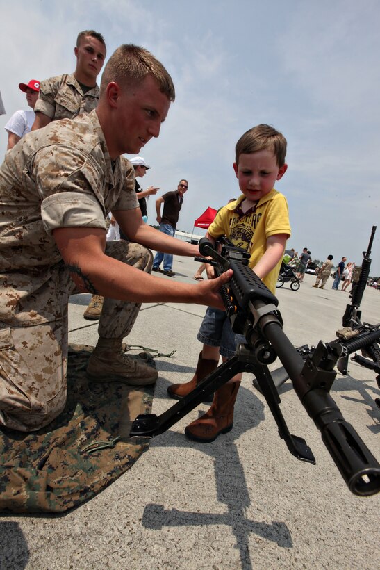 “It feels really heavy,” said Dylan Cochran as Lance Cpl. John Campbell, a machine gunner with Company A, 1st Battalion, 8th Marine Regiment, 2nd Marine Division, helps him lift an M240G machine gun at the 2011 Sounds of Freedom Air Show aboard Marine Corps Air Station New River, May 14.  1st Battalion, 8th Marines, provided static displays of current Marine Corps weapons systems.  Dylan is the son of Carrie and Sgt. Lewis Cochran, of the 22nd Marine Expeditionary Unit.