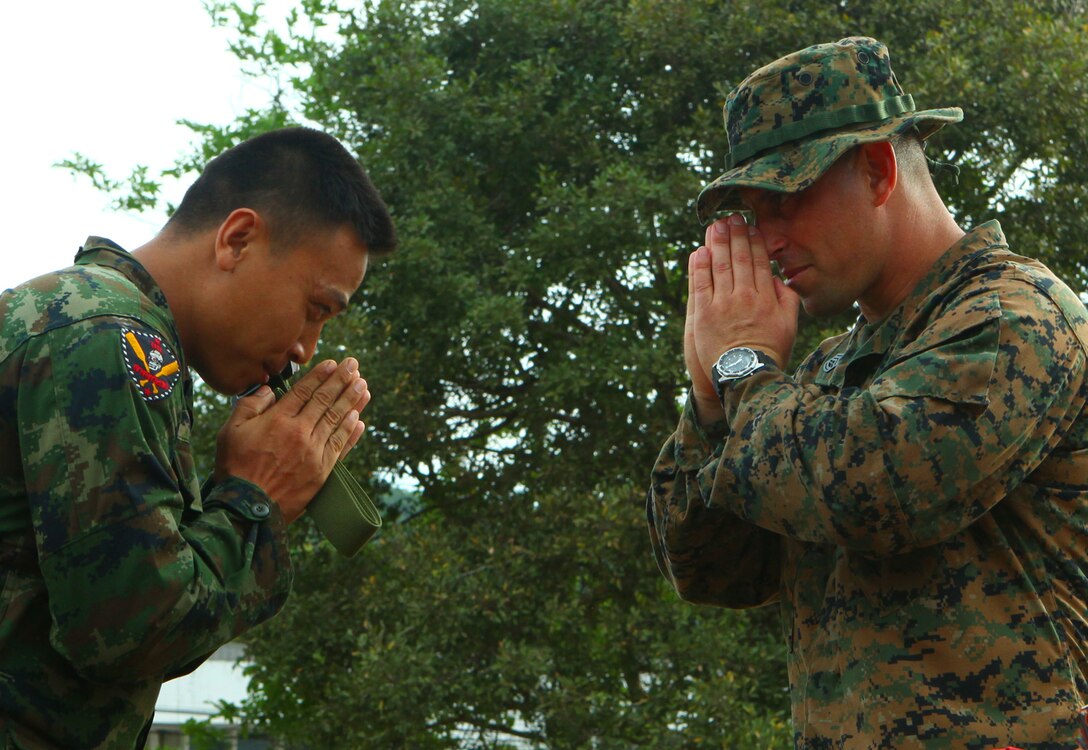 Gunnery Sgt. Victor Lopez, the Scout Sniper Chief Instructor with Weapons Platoon, Landing Force Company, bows to a Royal Thai Marine after presenting him with a green belt for being the most motivated student during the scout sniper training portion of Cooperation Afloat Readiness and Training (CARAT). Each student was awarded a 7.62 round on a 550 chord necklace as a symbol of accomplishment and camaraderie. CARAT is an annual bilateral exercise held in Southeast Asia with scenarios and training tailored with input from the U.S. and host countries to meet evolving threats, such as counter-piracy and maritime interdiction operations. Lopez is a reserve Marine with 2nd Battalion, 23 Marine Regiment, 4th Marine Division. (Official Marine Corps Photo by Cpl. Aaron Hostutler)