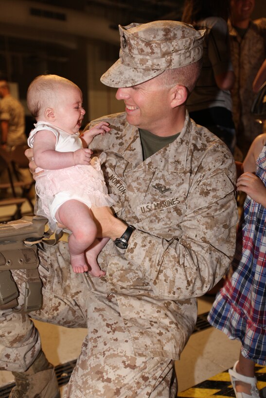 Maj. John C. Norton holds his daughter, Rowan, for the first time during the Marine Unmanned Aerial Vehicle Squadron 2 homecoming May 14. Rowan was born during VMU-2’s deployment to Afghanistan.
