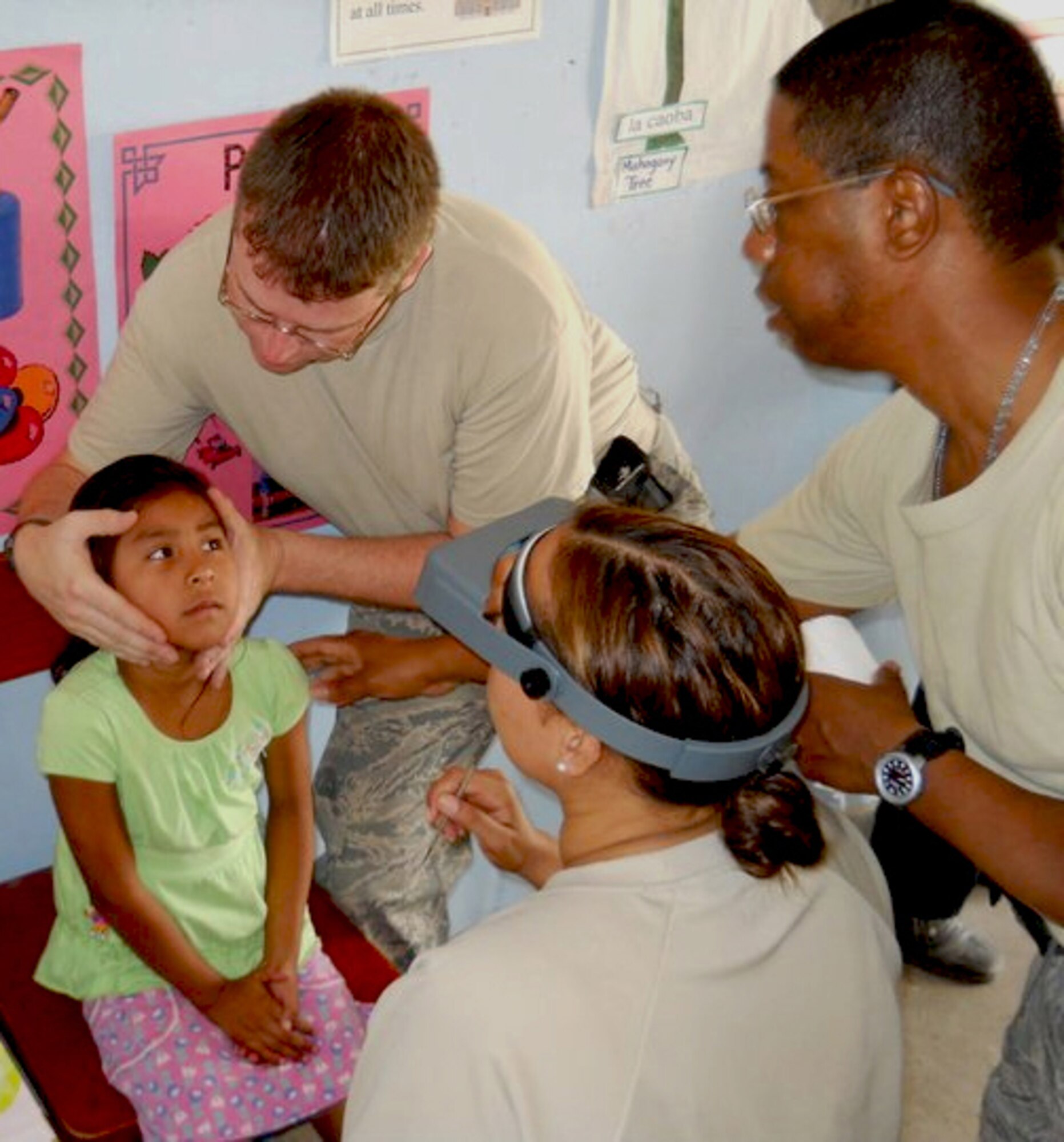 Master Sgt. Darrin Oglesby (top left) holds the head of a Belizean child in place while two unidentified Airmen stand by to assist in the performance of a medical procedure in this undated photo.  (U.S. Air Force photo)