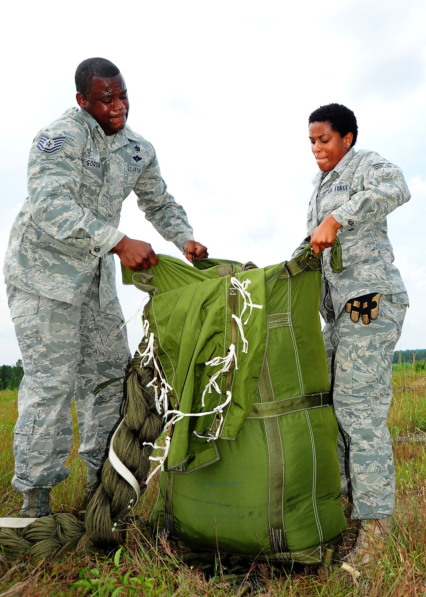 Tech. Sgt. Corey Gordon, 41st APS rigger, and Airman 1st Class Harriet Young, 41st APS, field pack the G-12 equipment parachute. (U.S. Air Force photo by Staff. Sgt Yolanda Addison)