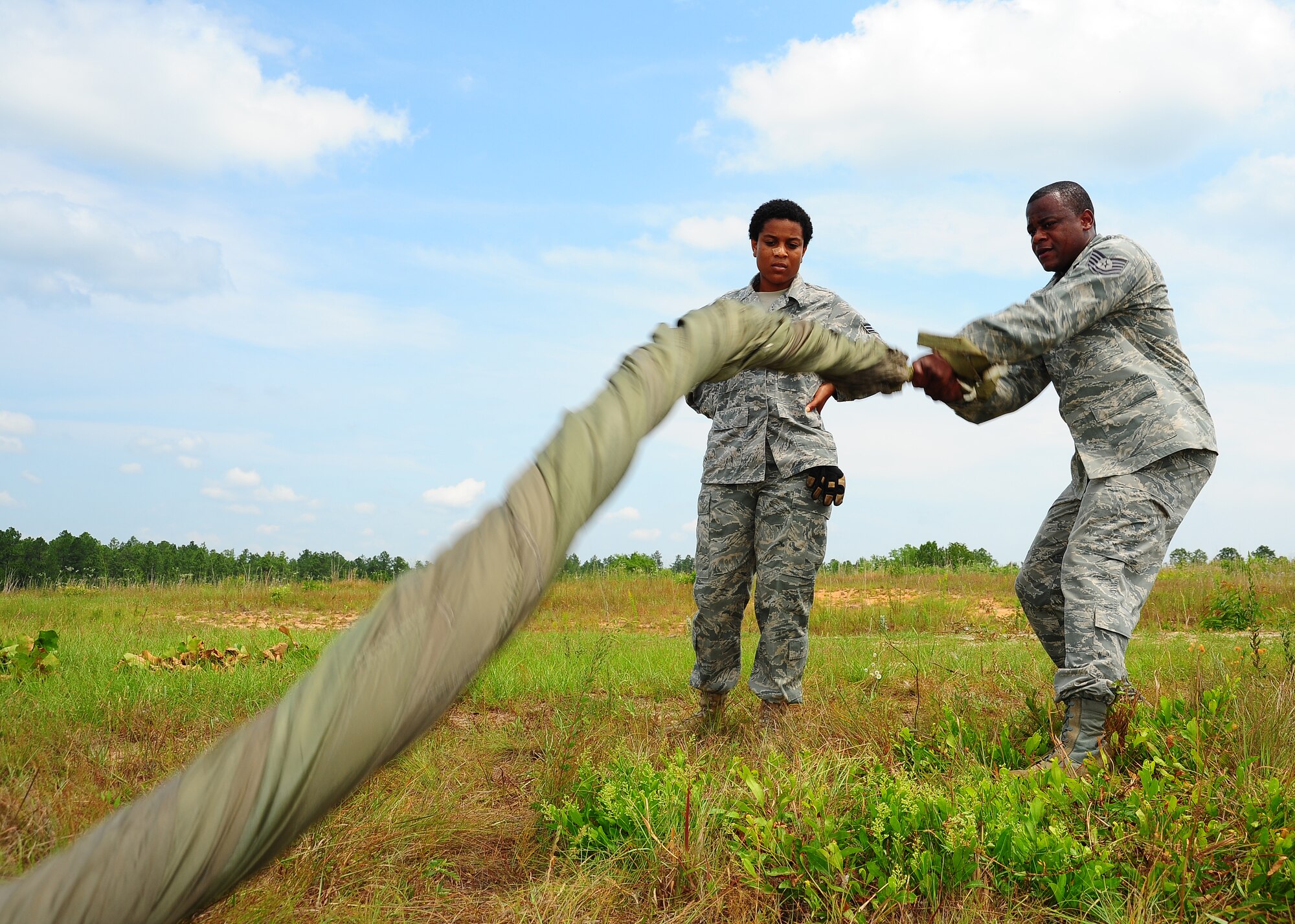 Tech. Sgt. Corey Gordon, 41st APS rigger, teaches Airman 1st Class Harriet Young, 41st APS, an easier way to "cigar roll" the G-12 equipment parachute. (U.S. Air Force photo by Staff. Sgt Yolanda Addison)