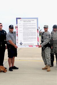 Donald Bond, Marine Resources Commission Law Enforcement Police officer in Newport News, Va., and Spc. Brian Williamson, 221st Military Police Detachment, hold the proclamation for Col. Donald Kirkland, 633d Air Base Wing commander, at Langley Air Force Base, Va., May 15, 2011. The signing marked the beginning of National Police Week, honoring all military and civilian defenders. (U.S. Air Force photo by Staff Sgt. Ashley Hawkins)(RELEASED)