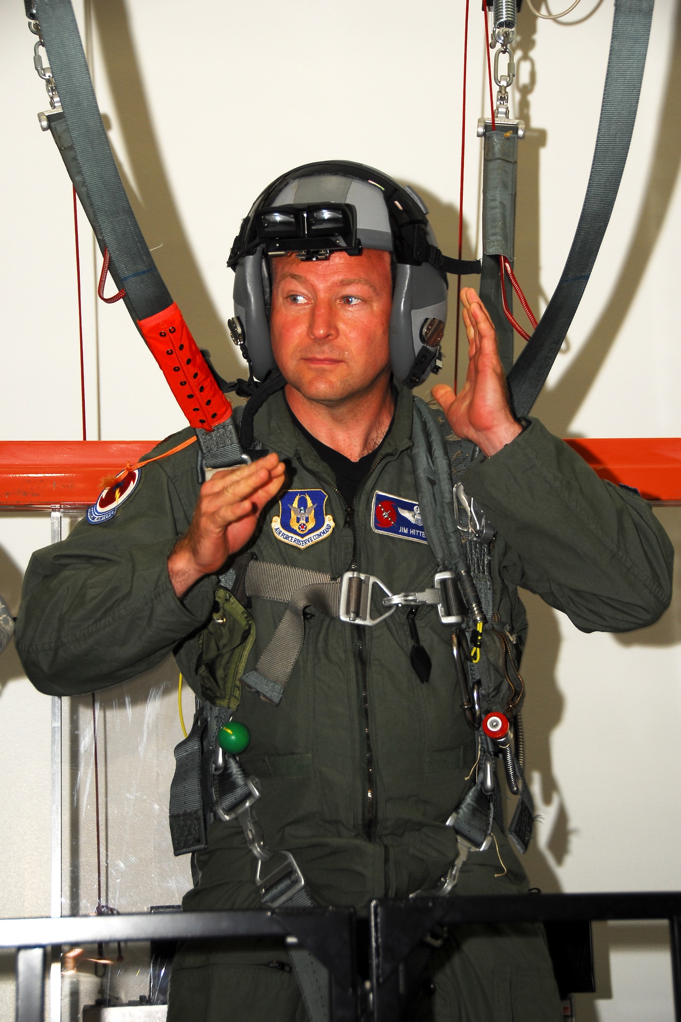Maj. Jim Hittermen, 53rd Weather Reconnaissance Squadron pilot, adjusts his helmet before simulating a parachuting jump. Aircrew members of the 403rd Wing are required to have annual parachute training and with the Virtual Reality Parachute Simulator, it makes it easier to stay current without leaving the ground. (U.S. Air Force photo by Staff Sgt. Tabitha Dupas)