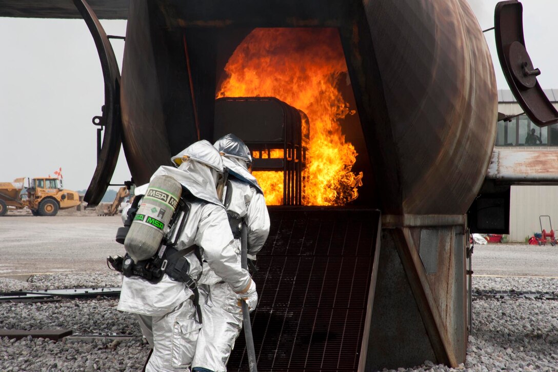 Senior Airman Rufus Watkins (right) and Airman 1st Class Clay Dixon, 403rd Civil Engineer Squadron firefighters, board a mock-up to put out an interior fire during a Live Fire Burn exercise at the Air National Guard Combat Readiness Training Center, Miss. As part of the handline crew, these Citizen Airmen tackle smaller fires on and around the airplane while the rescue crew extracts aircrew members and initiates engine shutdown. Firefighters need to know shutdown procedures for all aircraft assigned at their location. (U.S. Air Force photo by Tech. Sgt. Ryan Labadens)