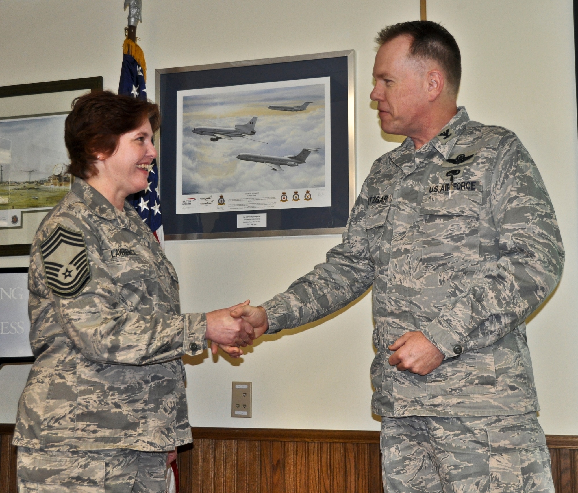 Chief Master Sgt. Kelly Lawrence, the 128th Air Refueling Wing command post superintendent, receives a Wing challenge coin from Col. Ted Metzgar, the 128th Air Refueling Wing commander, during a congratulatory handshake on Sunday, May 15, 2011.  Lawrence was promoted to the rank of chief master sergeant on Sunday during the Wing's May drill at Gen. Mitchell International Airport, Milwaukee.