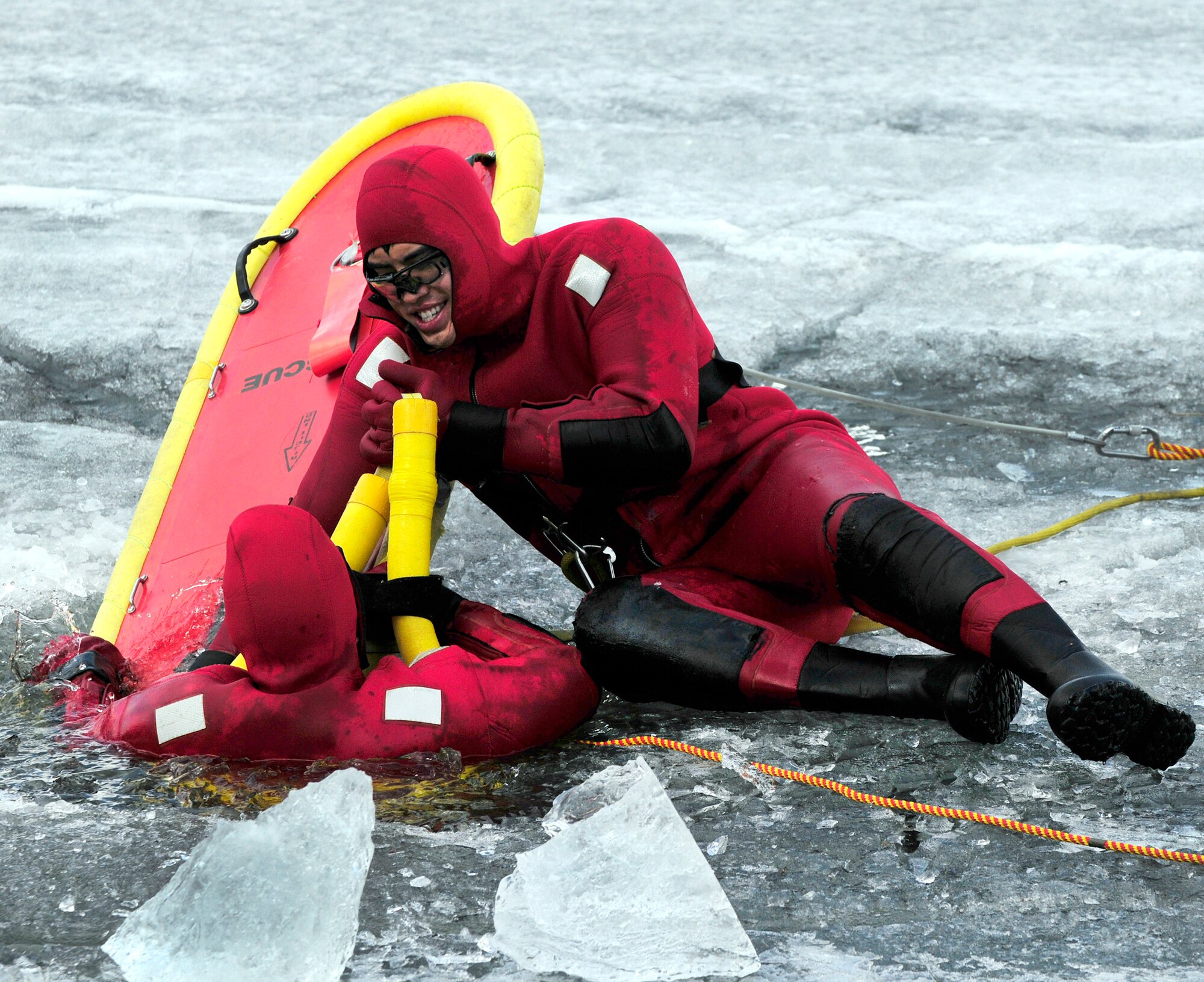 Airman 1st Class David Piasecki climbs out of a frozen lake onto a life raft that Senior Airman Bao Hoang stabilizes with his body during icy water rescue training May 6, 2011, at Eielson Air Force Base, Alaska. Airmen Hoang and Piasecki are fire fighters assigned to the 354th Civil Engineer Squadron Fire Protection Flight. (U.S. Air Force photo/Airman 1st Class Laura Goodgame)