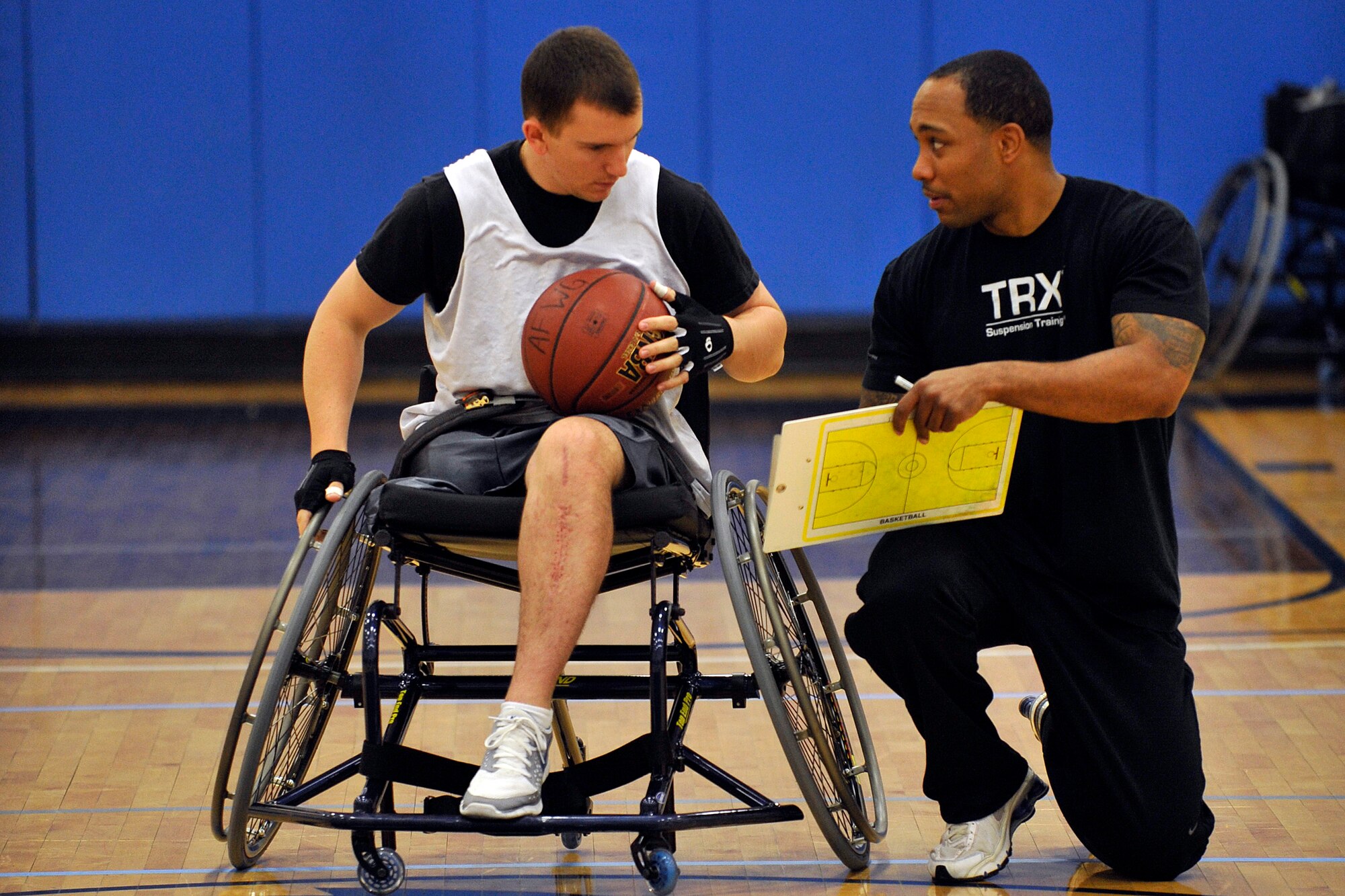 Air Force wheelchair basketball team assistant coach Corey Louis goes over a play with U.S. Air Force ROTC Cadet Matthew Perrillo during team practice May 12 in the Air Force Academy base gym. Perrillo lost his right leg and broke his left in a parachuting accident at the Academy last June. He and other Air Force wounded warriors are participating in the Warrior Games this week. (U.S. Air Force photo/Bill Evans)