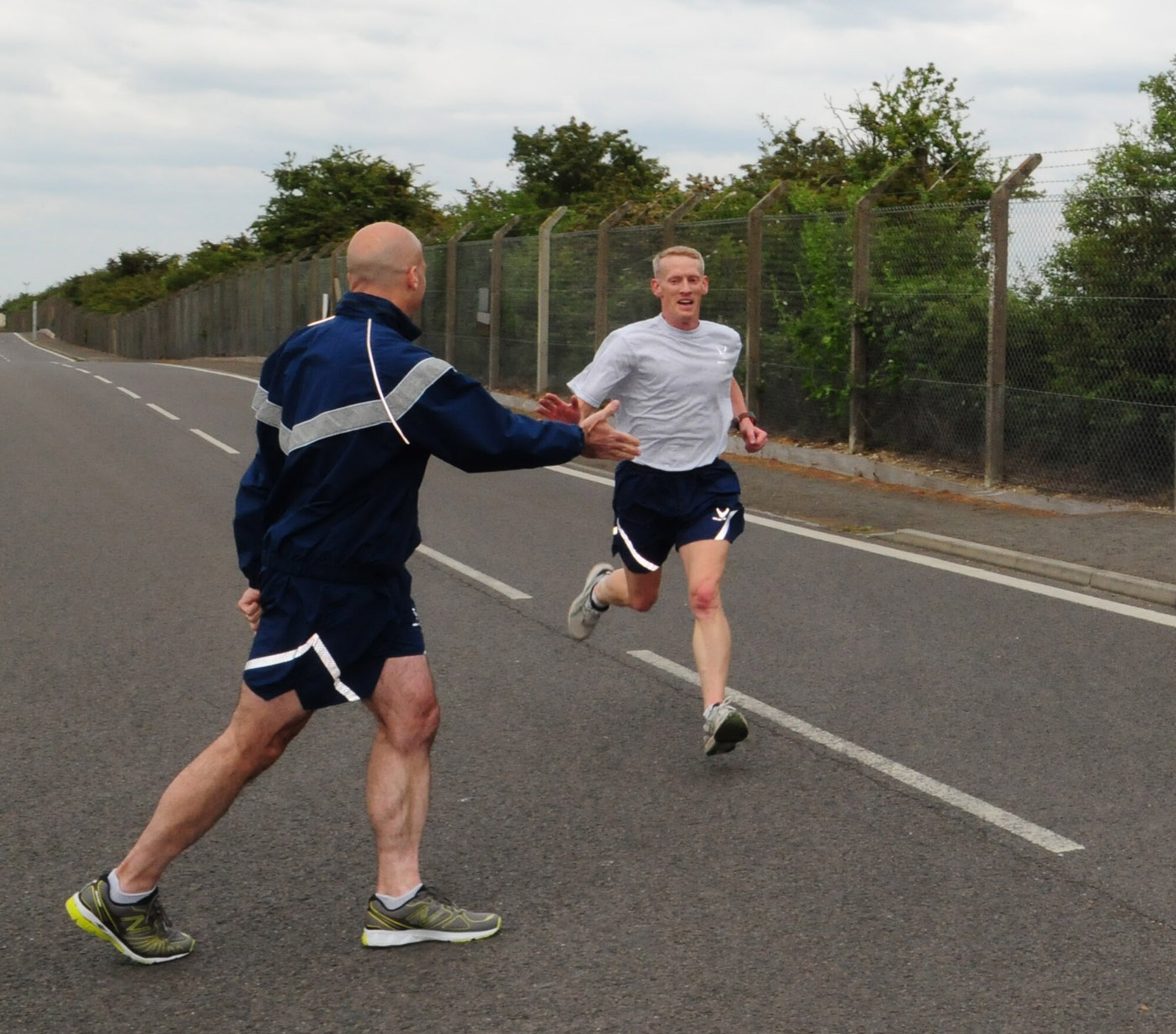 RAF MILDENHALL, England -- Lt. Col. Chris Bennett, 100th Air Refueling Wing Safety Office, is the first to cross the finish line May 13, 2011, after getting a High Five from Col. Chad Manske, 100th ARW commander. Colonel Bennett completed the run in 17:07. Tech. Sgt. Victor Hairston, 352nd Special Operations Support Squadron, placed joint second with 1st Lt. Shawn West, also 352nd SOSS, both with a time of 18:11. (U.S. Air Force photo/Karen Abeyasekere)