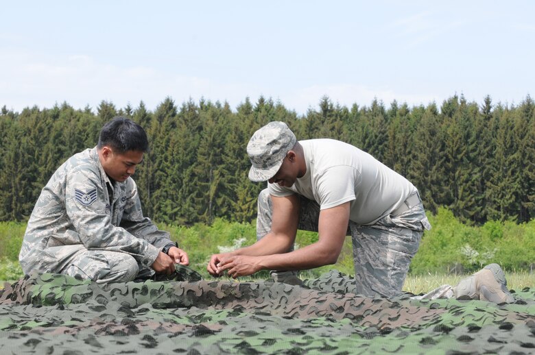 GEROLSTEIN, Germany – Staff Sgt. Alvin Delos Santos, left, 606th Air Control Squadron data systems technician, ties camouflage with Tech. Sgt. Modica Keenan, 606th ACS readiness NCO in charge, of as part of exercise Eifel Thunder 2011 in Gerolstein, Germany, May 9. The exercise tested the ability of Airmen to take all their equipment to an isolated location where they set up a deployed radar and satellite communications site as well as everything else required to survive and accomplish the mission in an isolated environment. (U.S. Air Force photo/Senior Airman Nick Wilson)