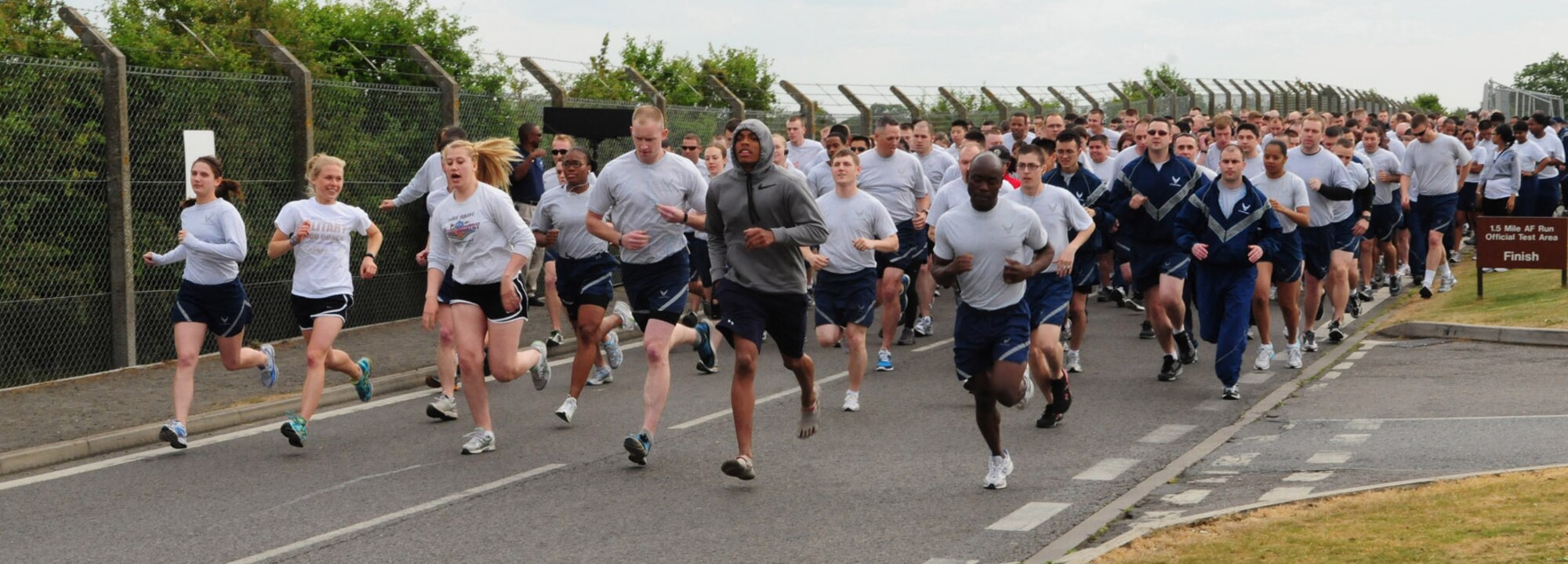 RAF MILDENHALL, England -- Members of Team Mildenhall race down Perimeter Road near the Hardstand Fitness Center and Hangar 814 at the start of the monthly 5K run May 13, 2011. The regular event is held to promote fitness and camaraderie among base members. (U.S. Air Force photo/Karen Abeyasekere)