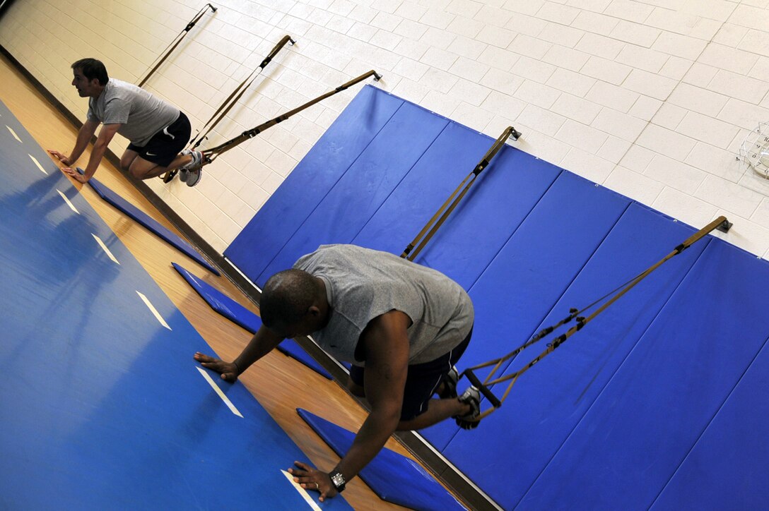 Jim Taccogno , spouse of 1st Lt. Sharee Taccogno, 633d Medical Group inpatient clinical nurse, and Maj. Freeman Holifield, Air Combat Command bioenvironmental engineer, perform a TRX Suspension Training exercise in the Shellbank Fitness Center at Langley Air Force Base, Va., May 10, 2011. TRX is a type of training in which you use your own body weight and gravity, to build strength, balance, coordination, flexibility, core and joint stability. (U.S. Air Force photo by Airman 1st Class Camilla Elizeu)(RELEASED) 