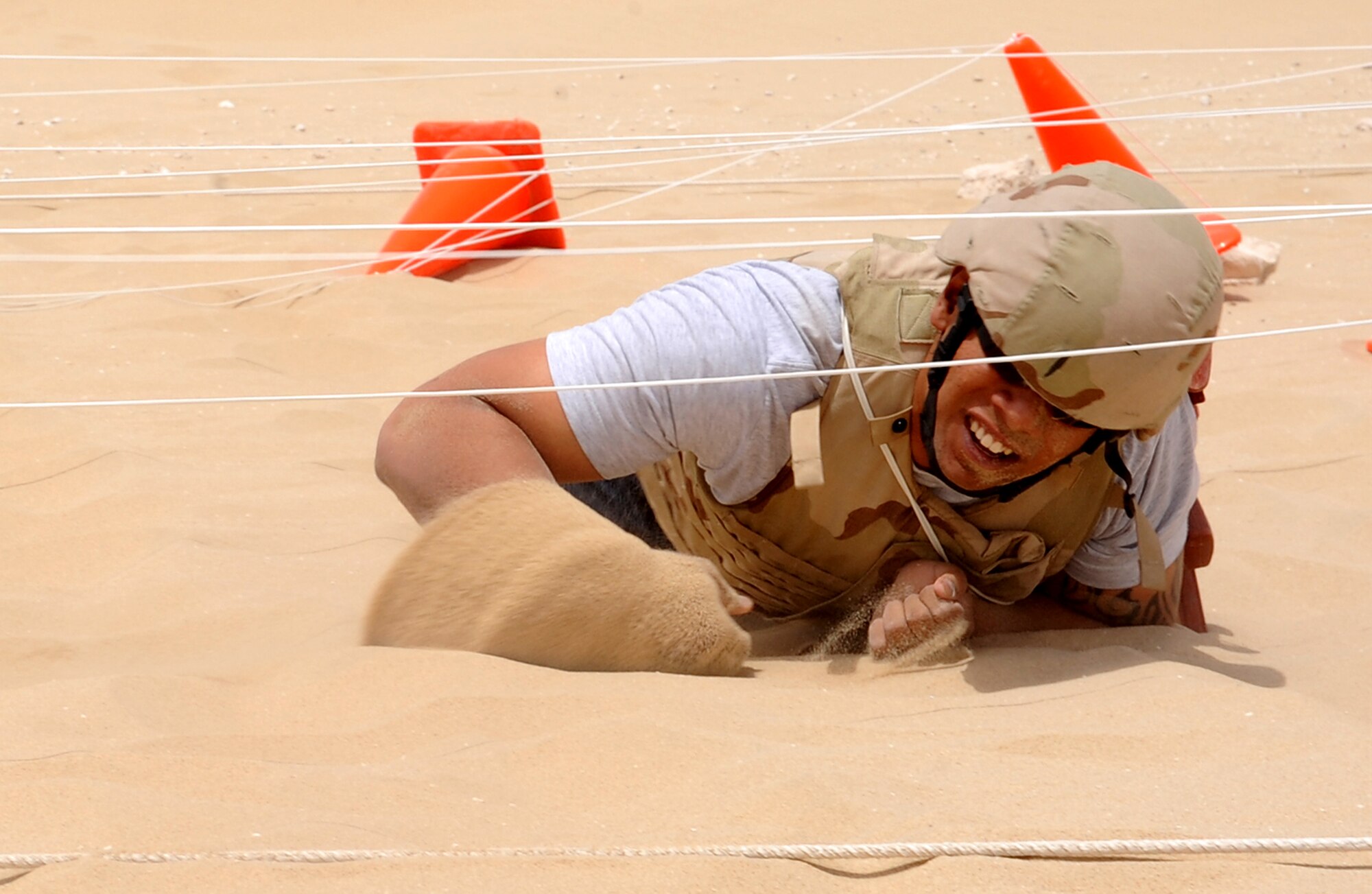 Senior Airman Nathan Namauu, 379th Expeditionary Security Forces Squadron, low crawls through the sand during the Defenders Challenge competition at an undisclosed location in Southwest Asia, May 15. Police Week honors those who fell defending others and also educates participants on the roles of police and security forces. (U.S. Air Force photo/Staff Sgt. Liliana Moreno)
