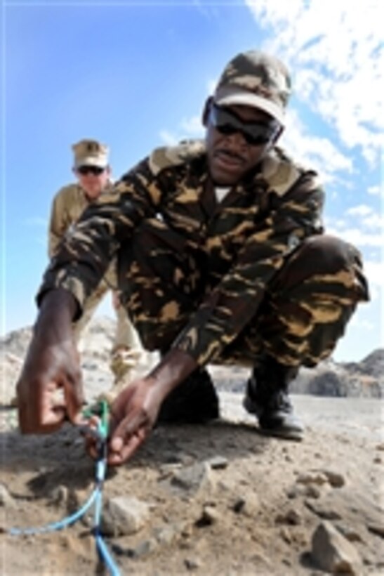 Namibian Defense Force Sgt. Eugene M. Salionga, an explosive ordnance technician student, attaches a non-electric blasting cap to the detonation priming loop as Chief Petty Officer Justin Berlien, assigned to Explosive Ordnance Disposal Mobile Unit 11, Combined Joint Task Force-Horn of Africa, looks on in Arandis, Namibia, on Apr. 28, 2011.  Navy EOD technicians and the Namibian Defense Force are engaging in a joint training seminar to enhance their understanding of safely handling and disposing of unexploded ordnance.  Explosive Ordnance Disposal Mobile Unit 11 is partnering with the Namibian Defense Forces EOD and Police Explosive Control Unit to support the Humanitarian Mine Action program by providing familiarization with International Mine Action Standards.  