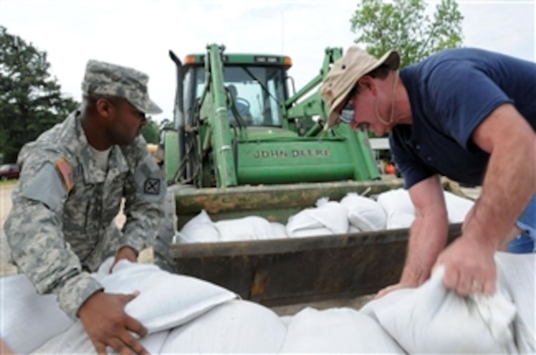A U.S. soldier (left) serving with the 77th Aviation Brigade of the Arkansas Army National Guard assists in the filling and placing of sandbags in areas affected by flooding of the White River in eastern Arkansas on May 9, 2011.  