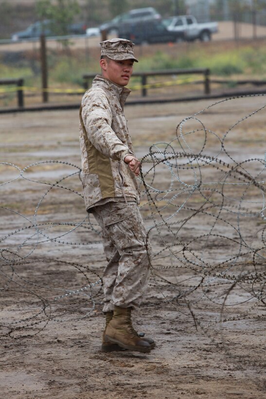 Daniel Kim, an intelligence analyst with 1st Intelligence Battalion I Marine Expeditionary Force, pulls Constantina wire at the Intelligence Operations Center here May 16. Kim, 19, born in Anaheim, Calif., is the youngest of six siblings.