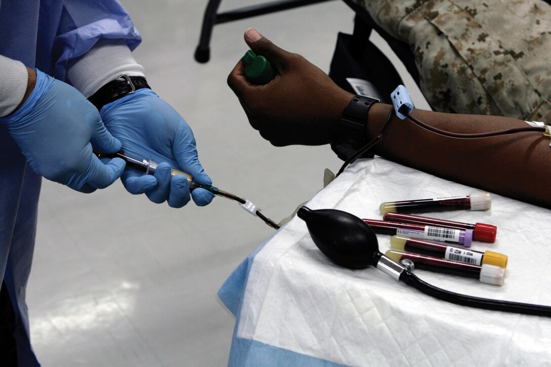 Petty Officer 1st Class Jun Villanueva, a medical lab technician with the U.S. Pacific Command Armed Services Blood Bank Center, collects individual vials during a blood donation by Pfc. Dewayne Schinault’s at a blood drive at building 494 on Camp Foster May 17. Schinault, along with more than 60 Marines and sailors belonging to the Joint Reception Center, donated blood to ASBBC. More information on donating blood and upcoming blood drives is also available at www.militaryblood.dod.mil/okinawa or on Facebook at www.facebook.com/okinawablood.com.