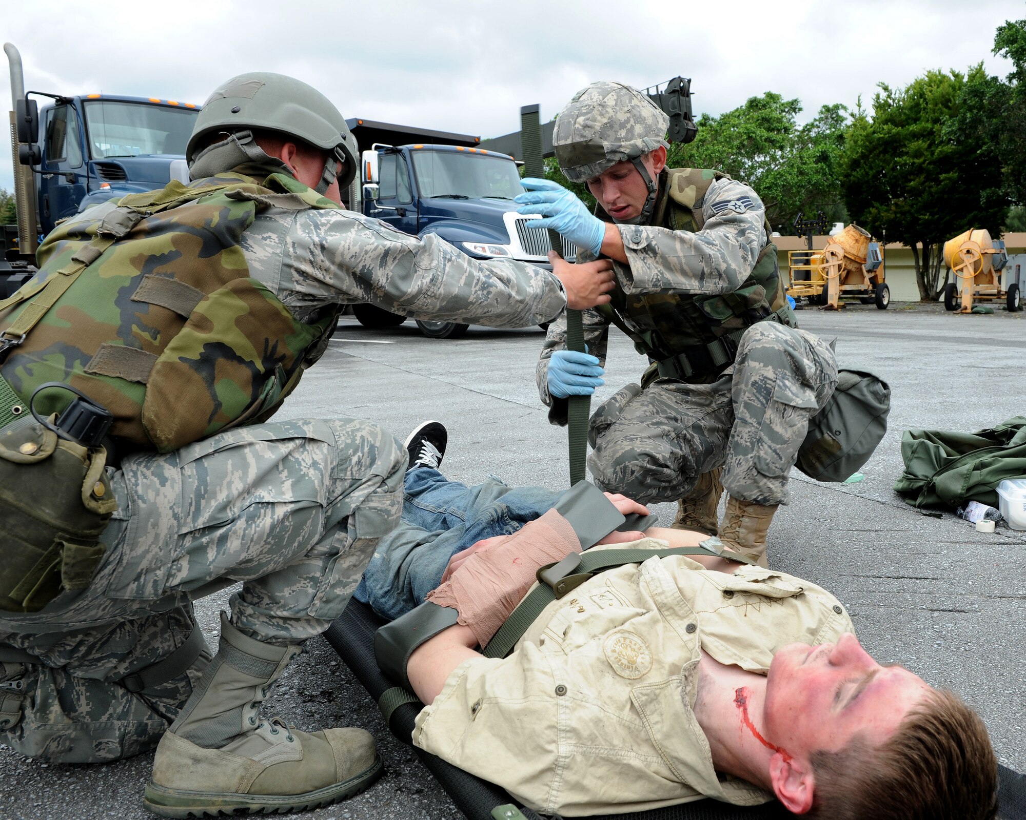 Senior Airman Cory Hasik (right) and Airman 1st Class Christopher Draper (left), both from the 18th Civil Engineer Squadron, load Airman 1st Class Malix Britton, 18th Equipment Maintenance Squadron, on to a litter to be transported to the hospital after he was “hit by a truck” and sustained multiple as part of local operational readiness exercise Beverly High 11-4, May 17, at Kadena Air Base, Japan. Kadena's personnel are participating in the LORE to stay prepared for real world contingencies. (U.S. Air Force photo/Junko Kinjo)