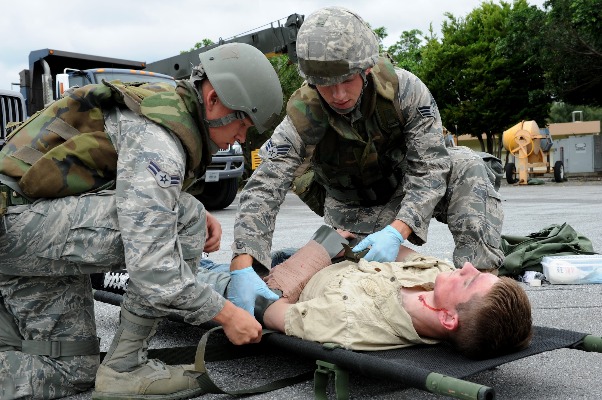 Senior Airman Cory Hasik (right) and Airman 1st Class Christopher Draper (left), both from the 18th Civil Engineer Squadron, load Airman 1st Class Malix Britton, 18th Equipment Maintenance Squadron, on to a litter to be transported to the hospital after he was “hit by a truck” and sustained multiple as part of local operational readiness exercise Beverly High 11-4, May 17, at Kadena Air Base, Japan. Kadena's personnel are participating in the LORE to stay prepared for real world contingencies. (U.S. Air Force photo/Junko Kinjo)