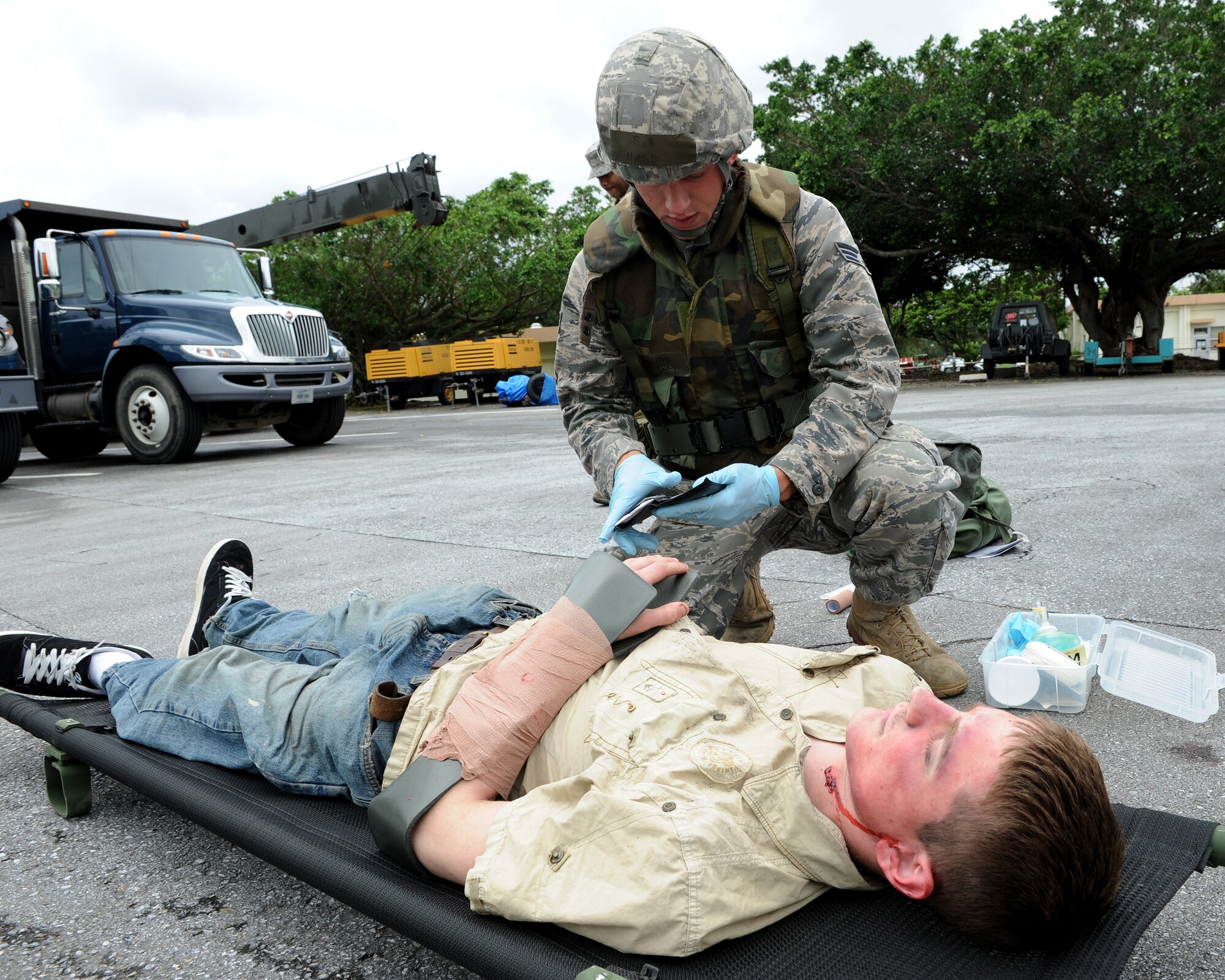 Senior Airman Cory Hasik, 18th Civil Engineer Squadron, searches through a wallet to identify “injured” Airman 1st Class Malix Britton, 18th Equipment Maintenance Squadron, who is simulating being hit by a truck as part of local operational readiness exercise Beverly High 11-4, May 17, at Kadena Air Base, Japan. Kadena's personnel are participating in the LORE to stay prepared for real world contingencies. (U.S. Air Force photo/Junko Kinjo)