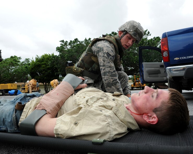 Senior Airman Cory Hasik, 18th Civil Engineer Squadron, applies self aid and buddy care to “injured” Airman 1st Class Malix Britton, 18th Equipment Maintenance Squadron, who is simulating being hit by a truck as part of local operational readiness exercise Beverly High 11-4, May 17, at Kadena Air Base, Japan. Kadena's personnel are participating in the LORE to stay prepared for real world contingencies. (U.S. Air Force photo/Junko Kinjo)