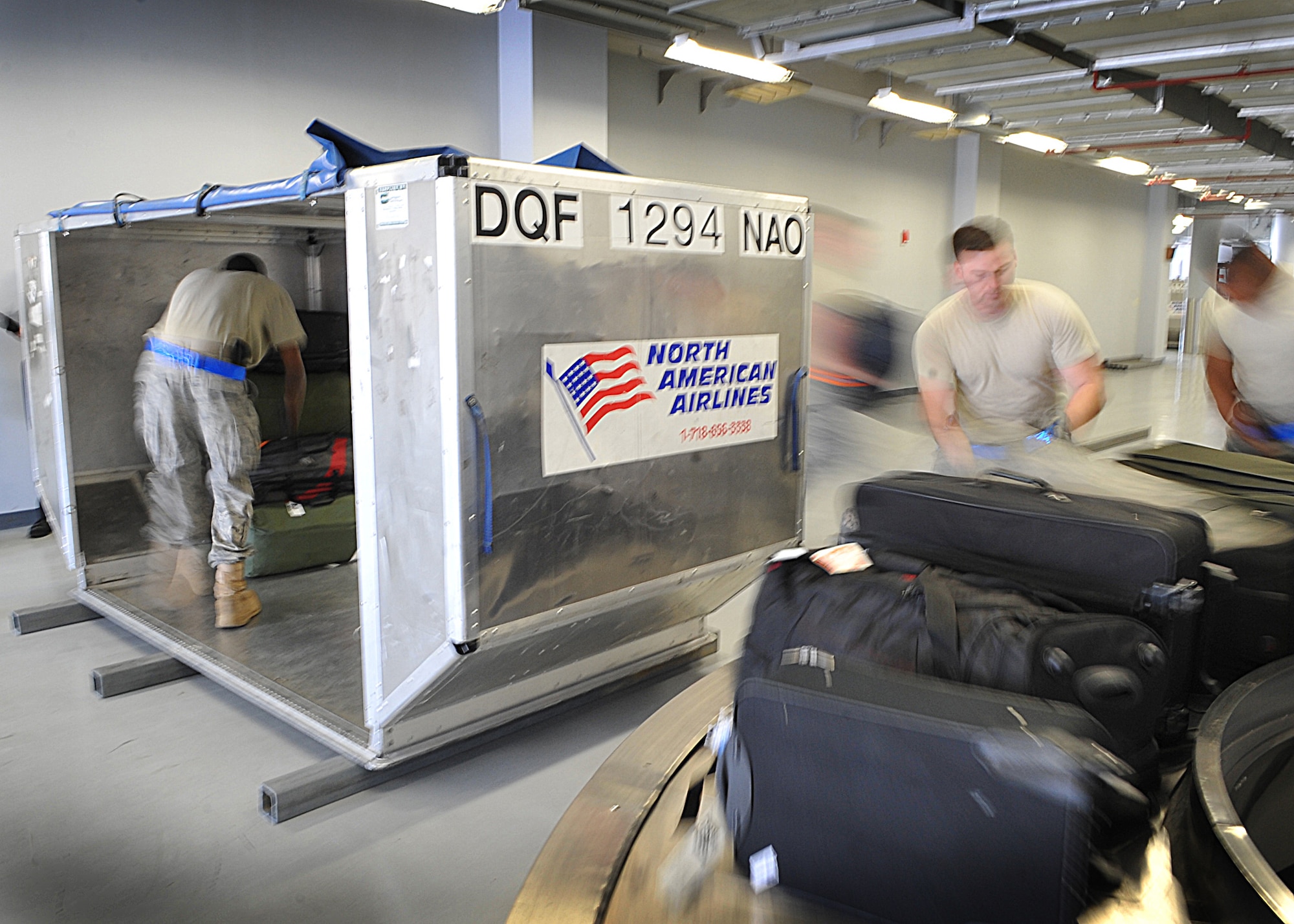 731 Air Mobility Squadron Airmen unload passangers baggage onto a moving belt belt, May 17 . (U.S. Air Force Photo by Senior Airman Evelyn Chavez)