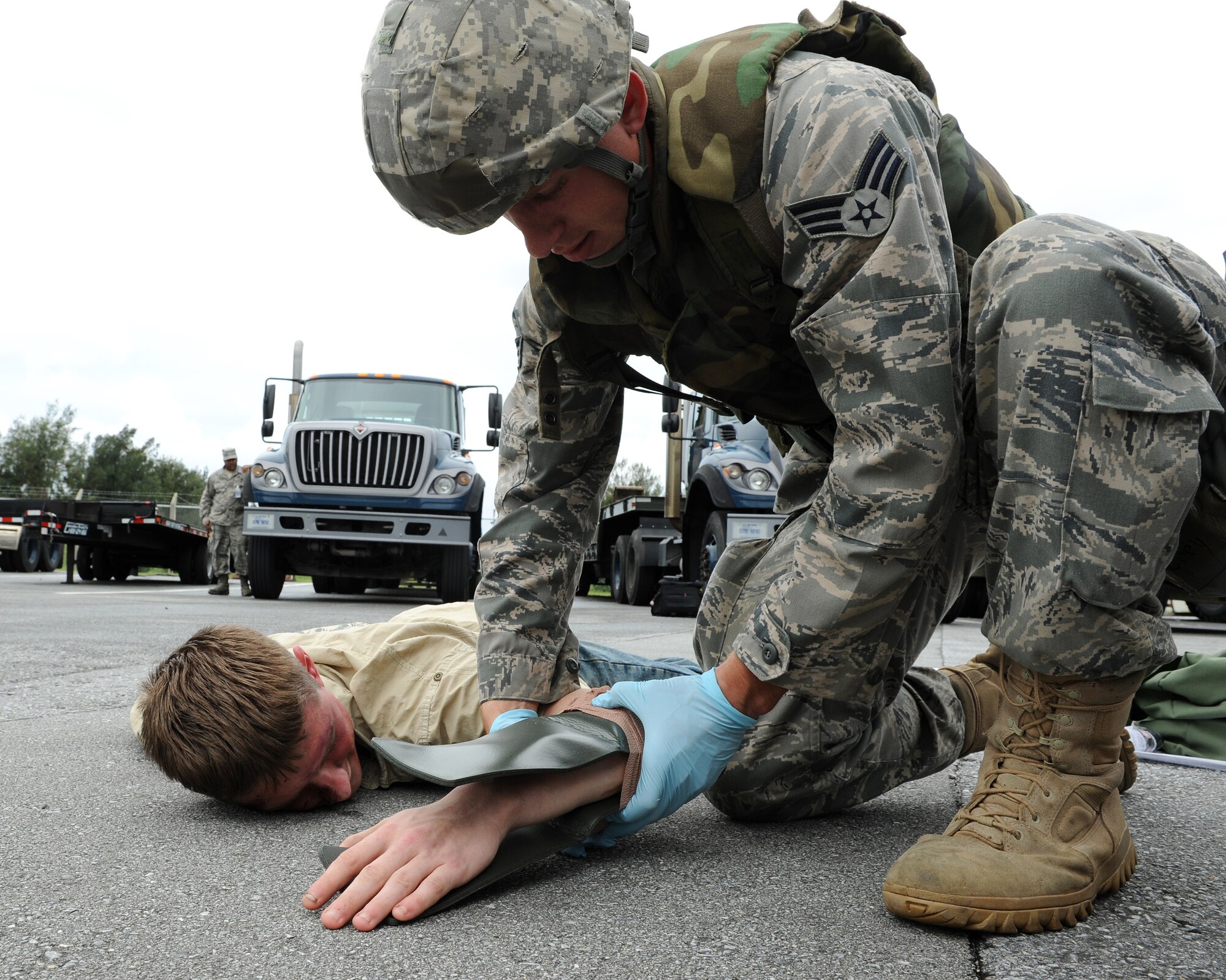 Senior Airman Cory Hasik, 18th Civil Engineer Squadron, applies self aid and buddy care to “injured” Airman 1st Class Malix Britton, 18 Equipment Maintenance Squadron, who is simulating being hit by a truck as part of local operational readiness exercise Beverly High 11-4, May 17, at Kadena Air Base, Japan. Kadena's personnel are participating in the LORE to stay prepared for real world contingencies. (U.S. Air Force photo/Junko Kinjo)