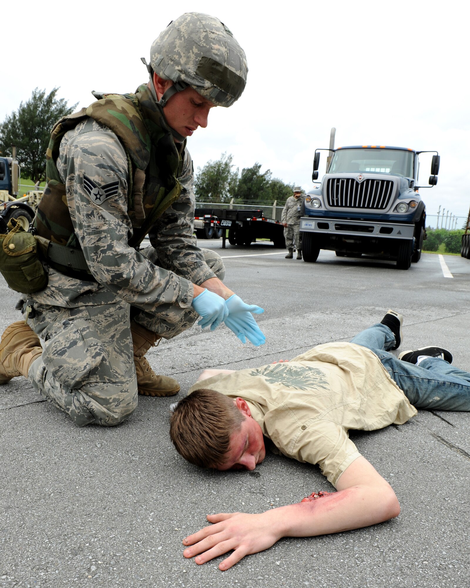 Senior Airman Cory Hasik, 18th Civil Engineer Squadron, applies self aid and buddy care to “injured” Airman 1st Class Malix Britton, 18 Equipment Maintenance Squadron, who is simulating being hit by a truck as part of local operational readiness exercise Beverly High 11-4, May 17, at Kadena Air Base, Japan. Kadena's personnel are participating in the LORE to stay prepared for real world contingencies. (U.S. Air Force photo/Junko Kinjo)